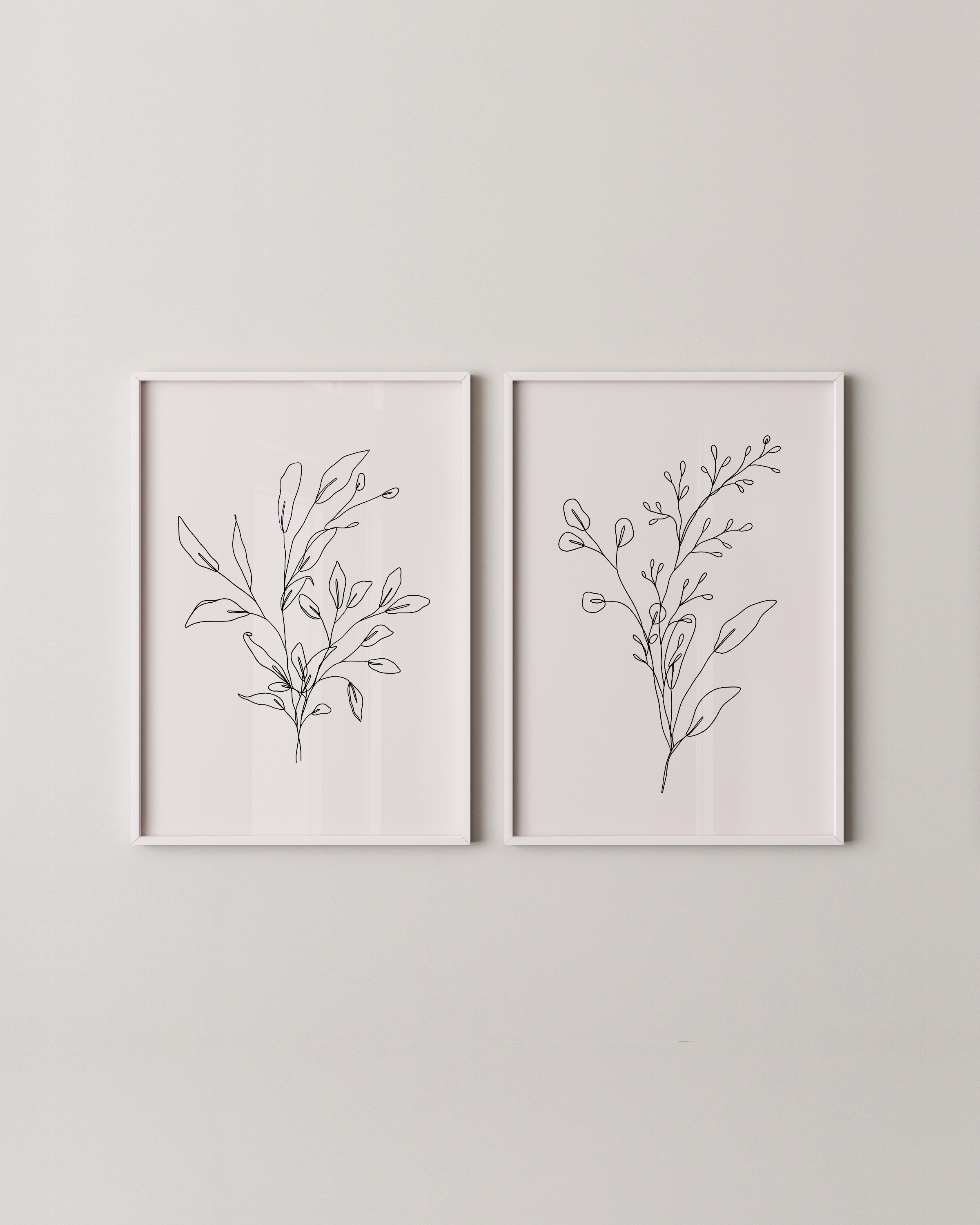 Set of two minimalist black and white botanical line drawings, each featuring a unique leafy branch sketch on a white background.