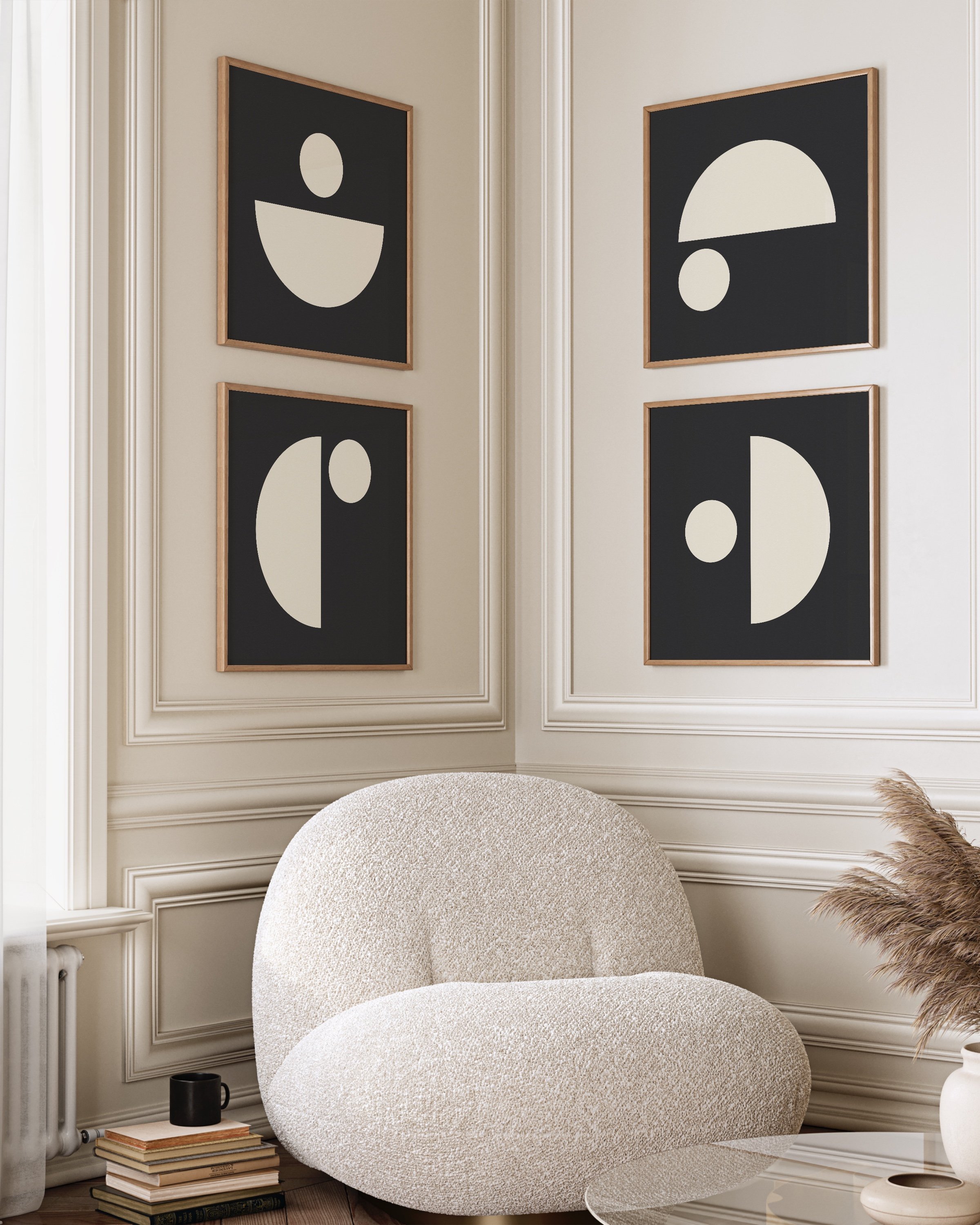 Modern minimalist geometric wall art set featuring black and cream abstract shapes, displayed in wooden frames on a neutral wall with a cozy armchair and natural decor elements.
