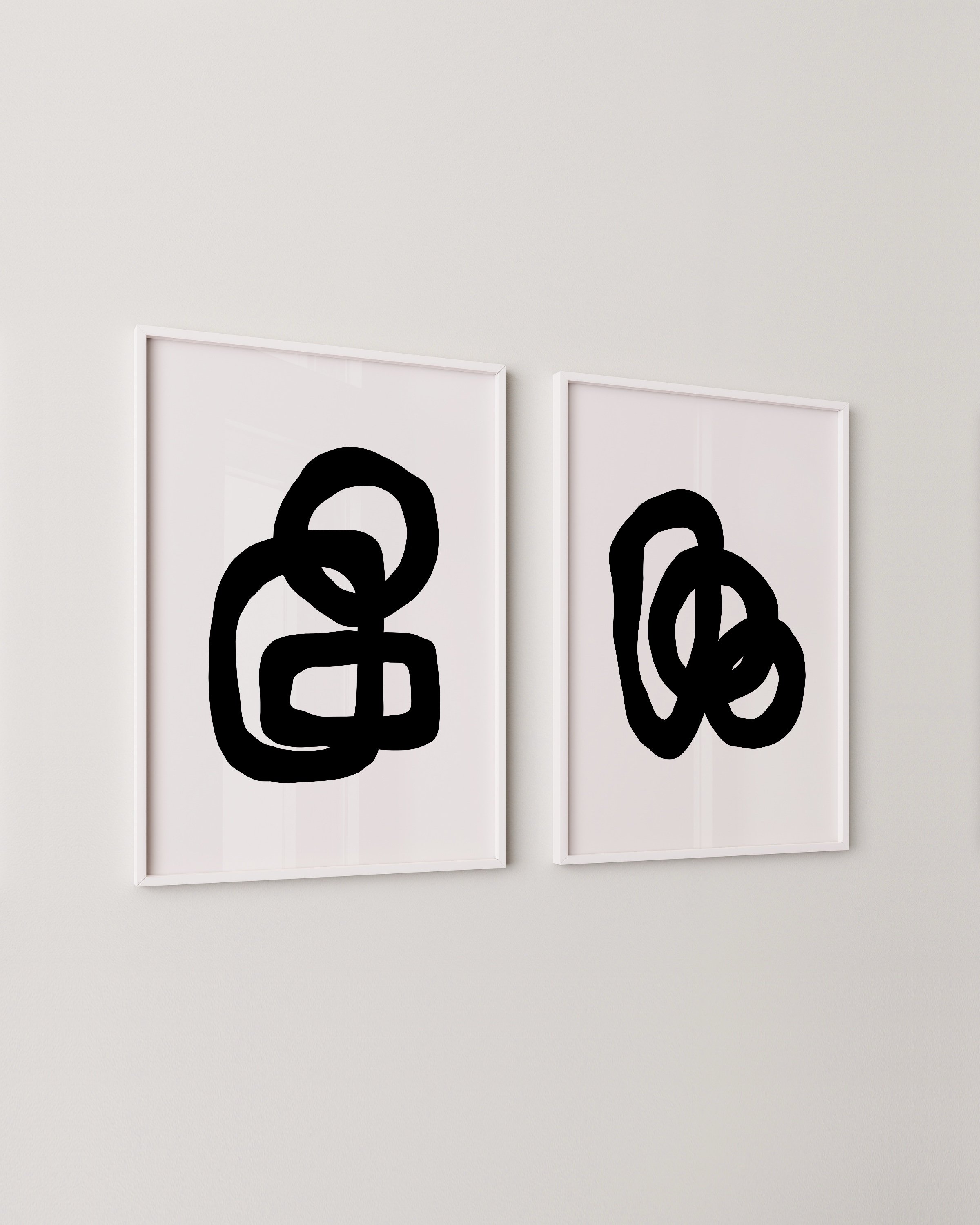 Minimalist abstract art prints featuring bold black loops on white backgrounds, framed in white and displayed as a contemporary art duo.