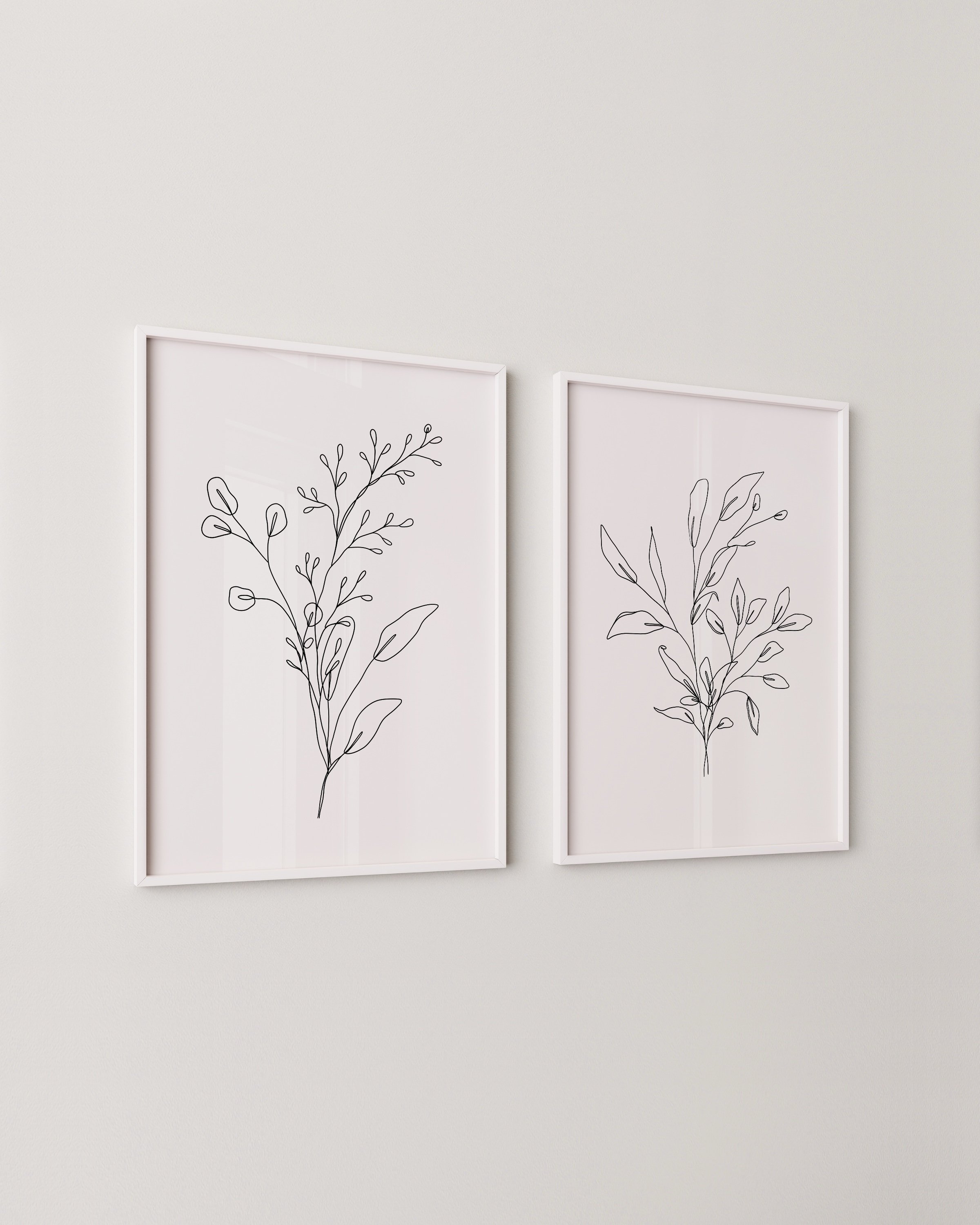 Set of two minimalist black and white botanical line drawings, each featuring a unique leafy branch sketch on a white background.