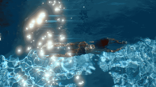 A person floating on a swimming pool surface with sunlight reflecting and sparkling on the water.