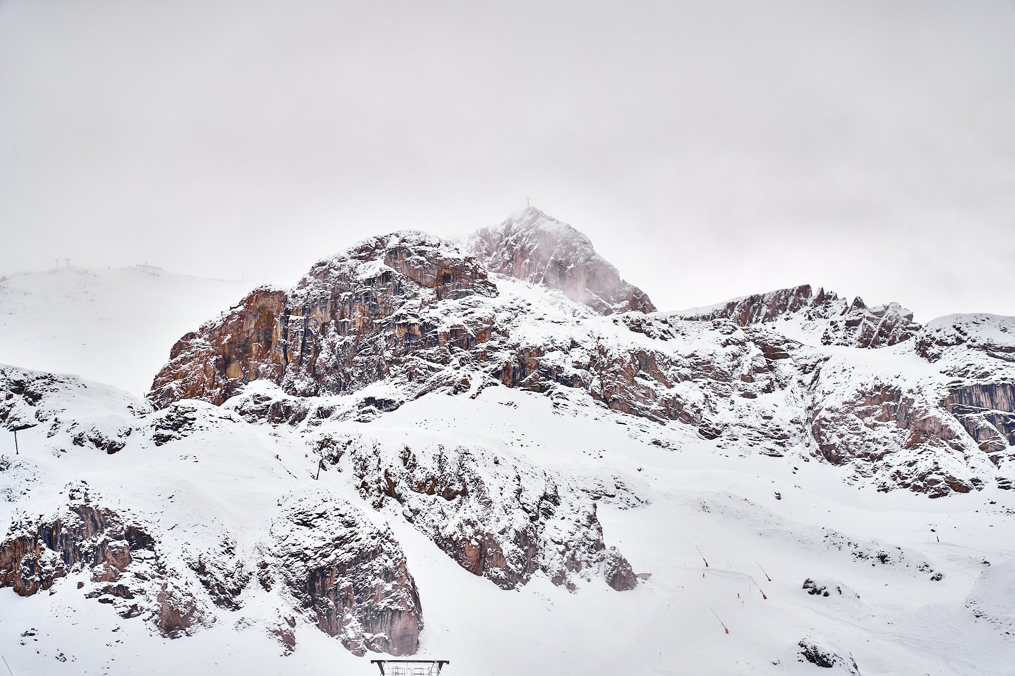 Snow-covered mountain with rocky formations and ski lifts at the base.