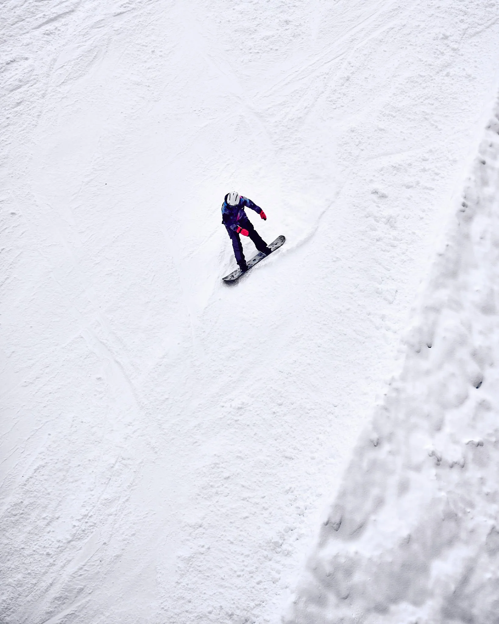 A person wearing a helmet and winter gear snowboarding down a snowy slope.