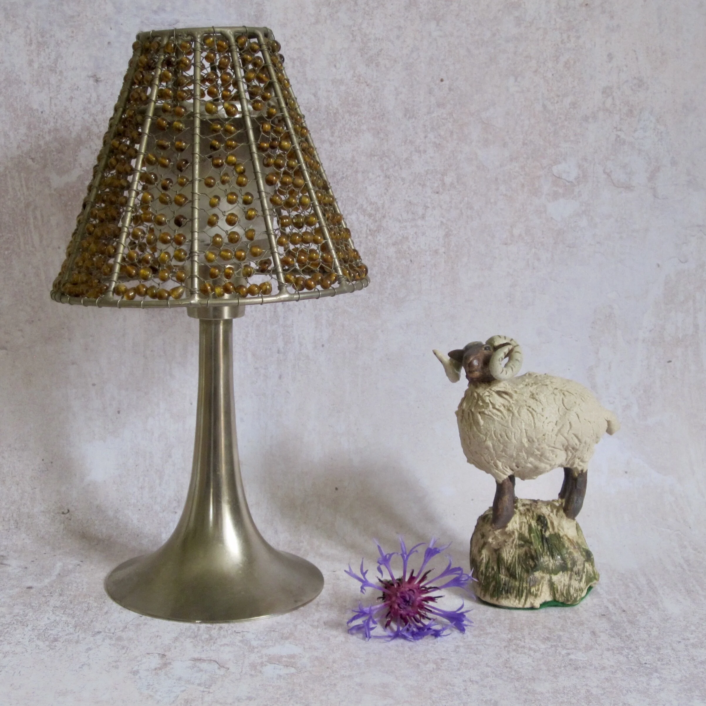 Life style of view of hand sculpted ceramic sheep standing on a rock