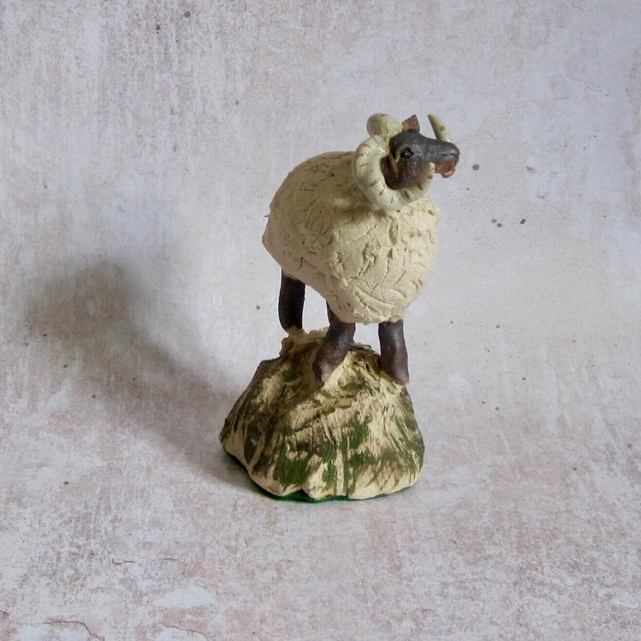 View of hand sculpted ceramic sheep standing on a rock