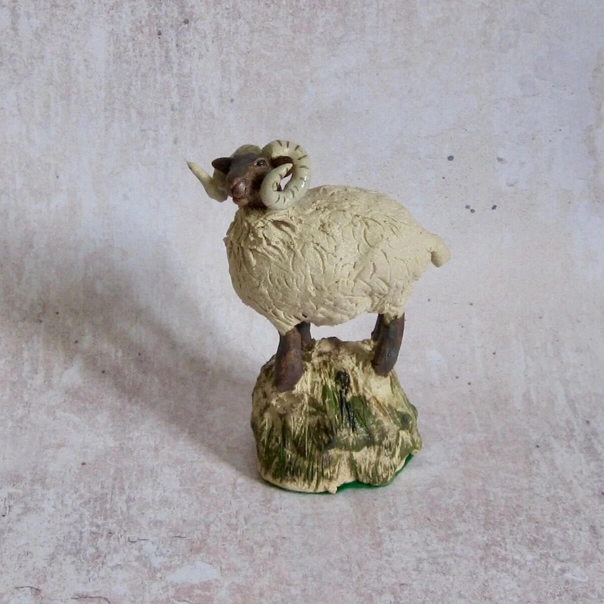 View of hand sculpted ceramic sheep standing on a rock