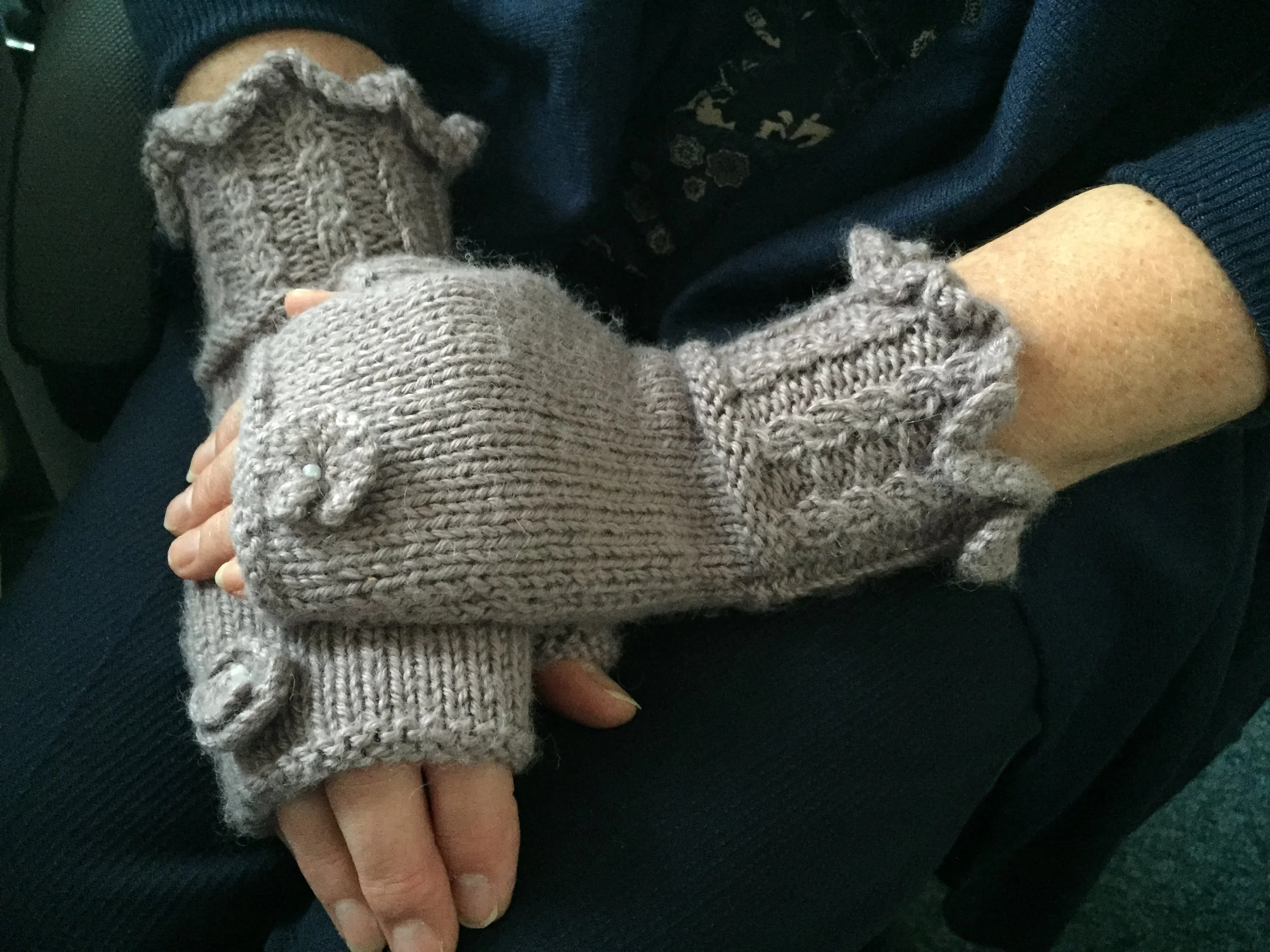 hands wearing blossom mitts - knitted mitts with flower attached