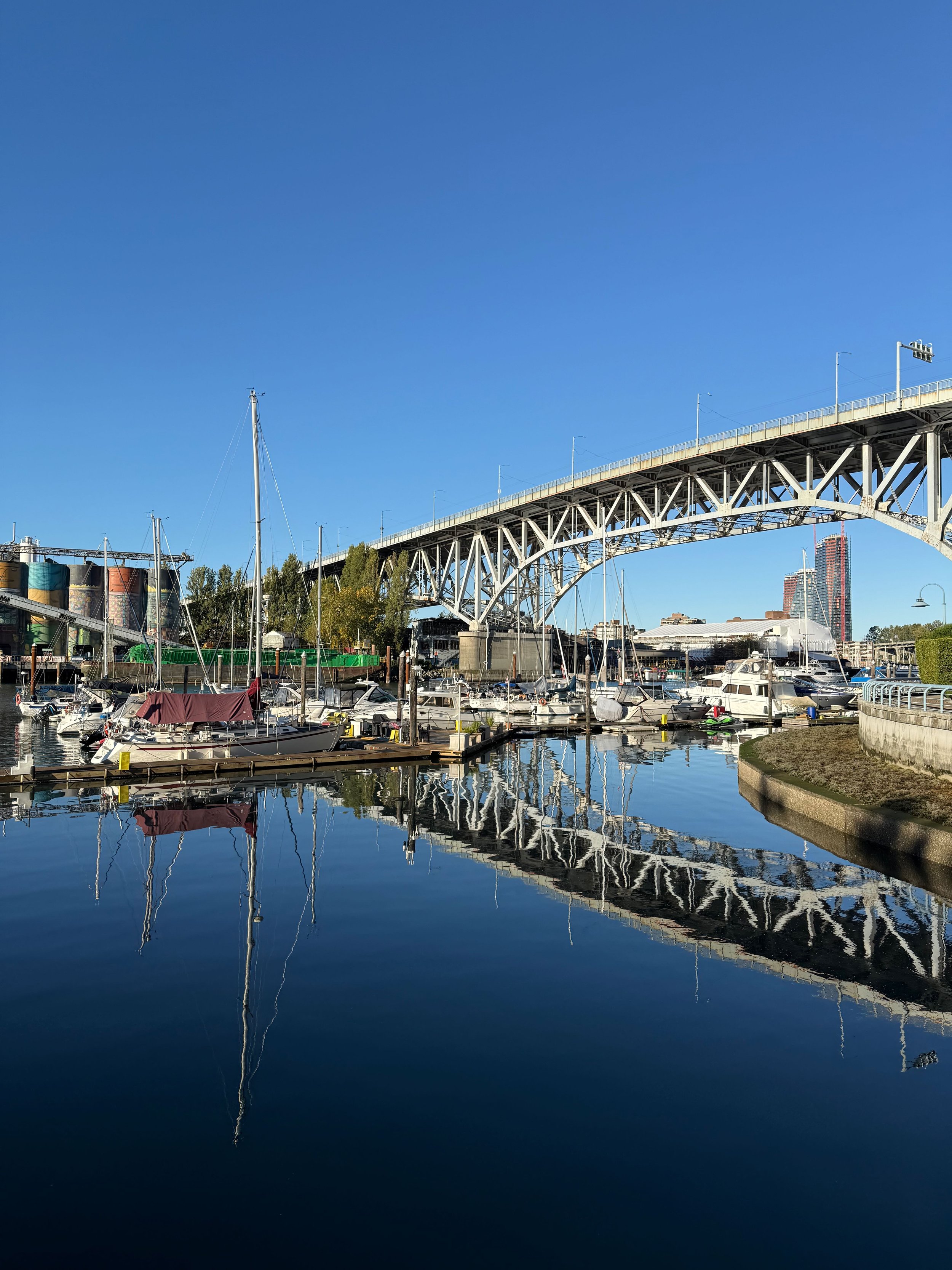 Still water, bright sky, and a quiet marina — a calm Vancouver moment where architecture and nature meet.