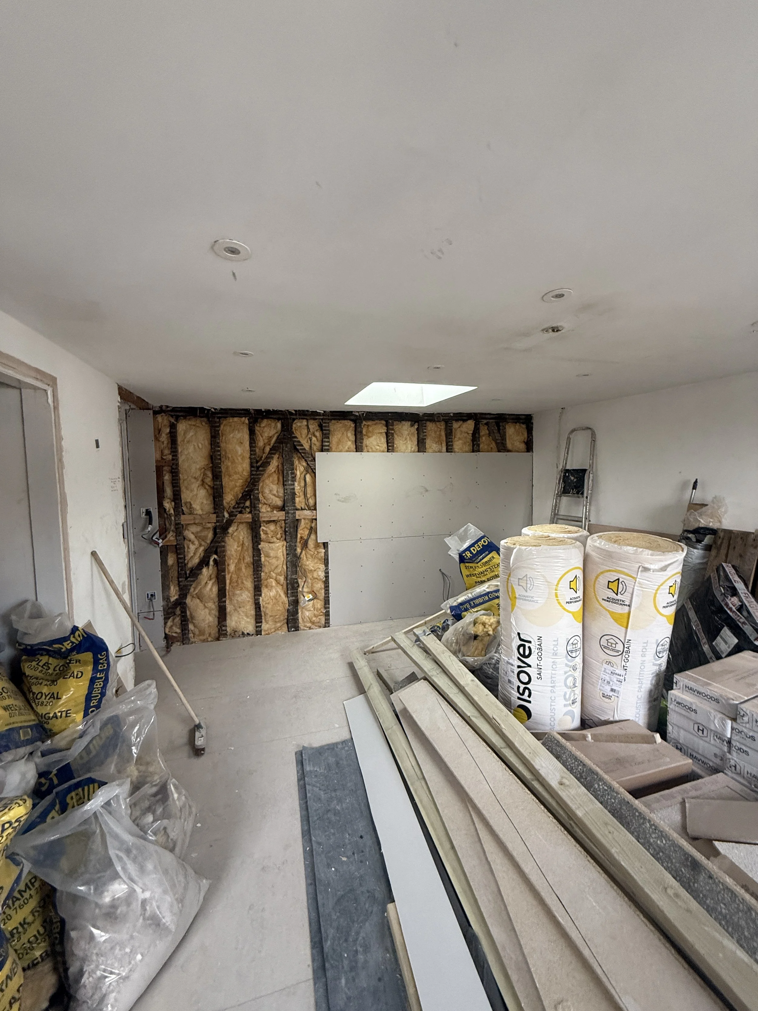 Wall showing new insulation fitted and the first sheet of plasterboard installed.