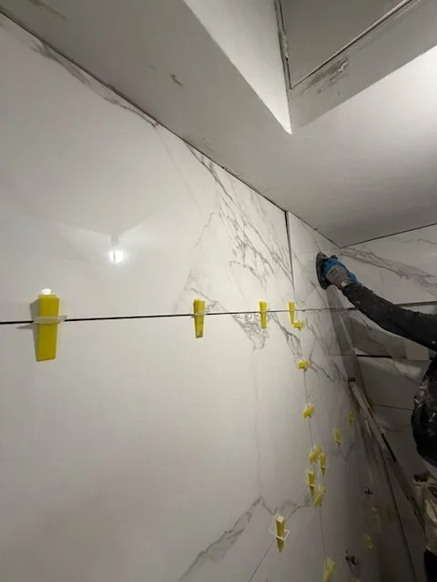 Upper wall tile finishing during London studio bathroom renovation