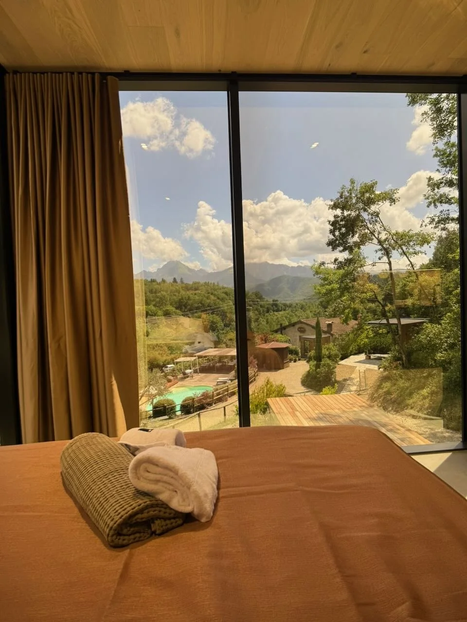 bedroom with folded towels on the bed and large window overlooking tuscan hills