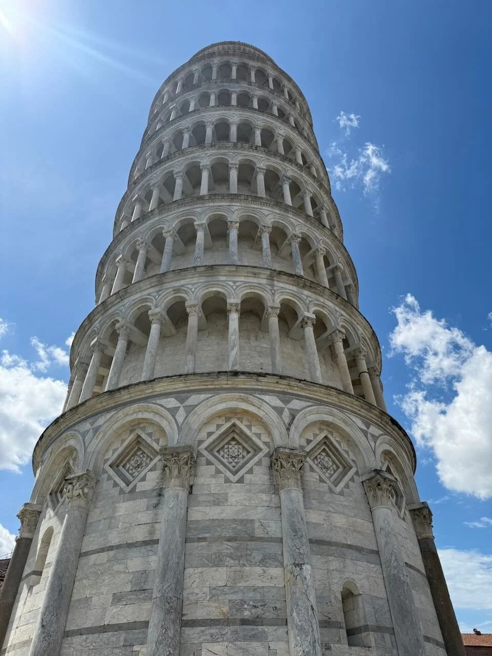 close-up view looking up at the leaning tower of pisa against a blue sky