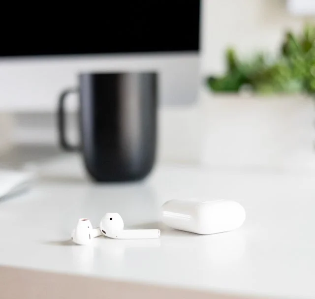 Minimal white workspace with AirPods and soft light, symbolising seamless digital connection across cities.
