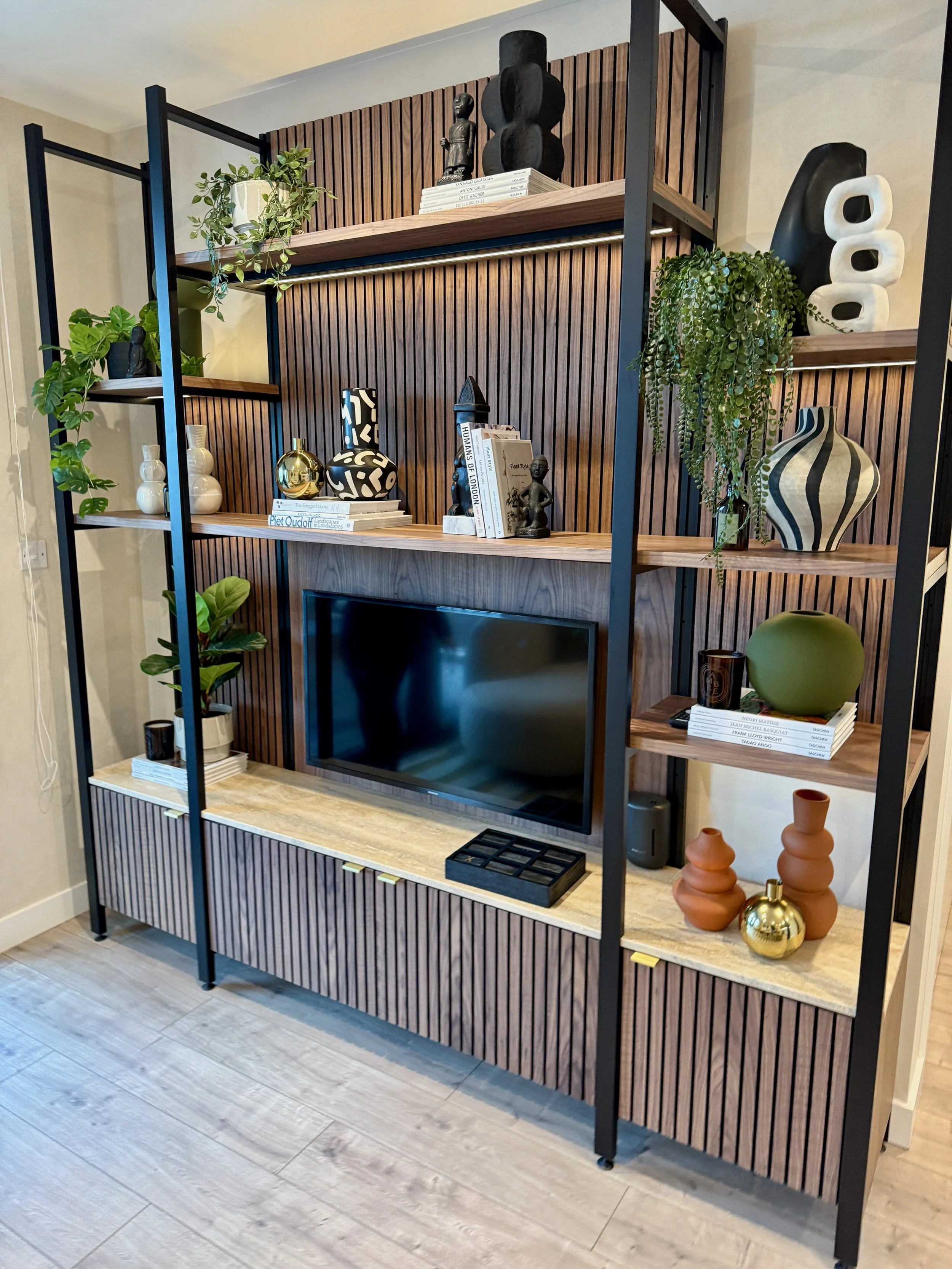 “Industrial wood and metal shelving with bar setup and curated design books.”