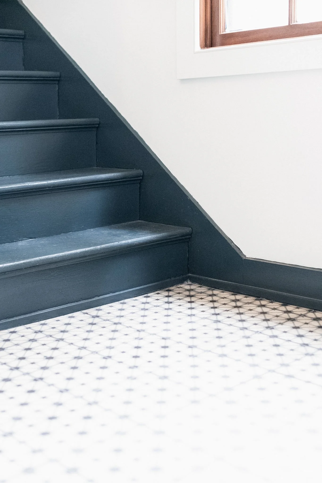 Deep blue painted staircase against white walls with minimal patterned floor tiles, clean lines and quiet architectural contrast.