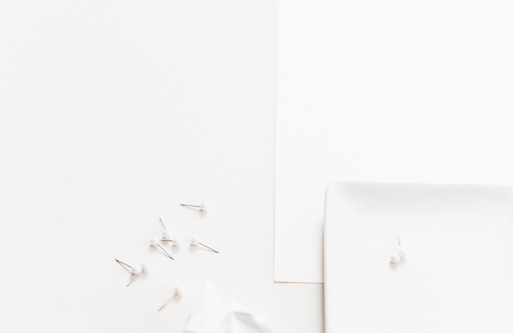 A calm, spacious desk scene with scattered white pins and paper, representing the open, flexible workflows that support modern creative work paths.
