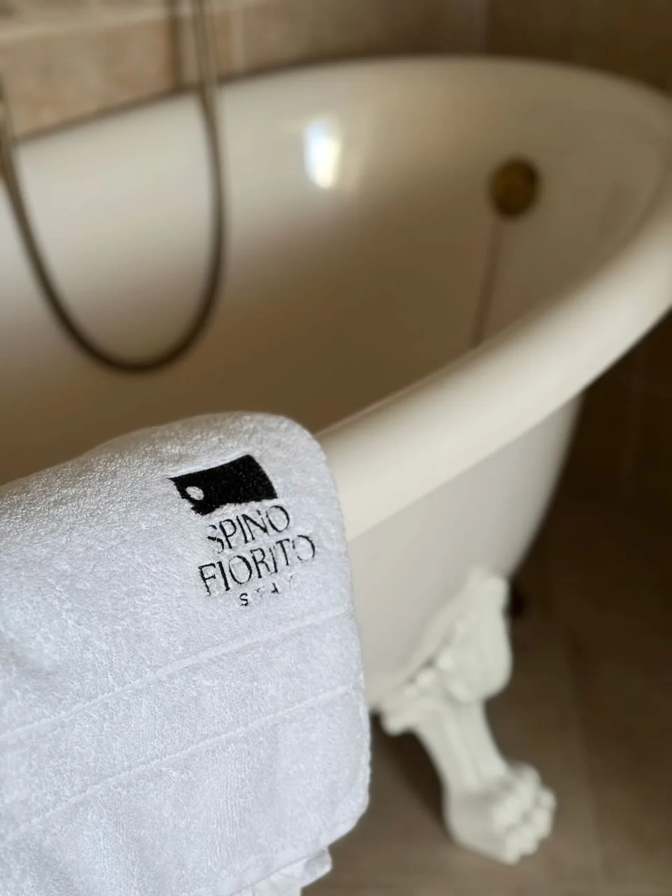 A branded bath towel from Spino Fiorito placed over a bath