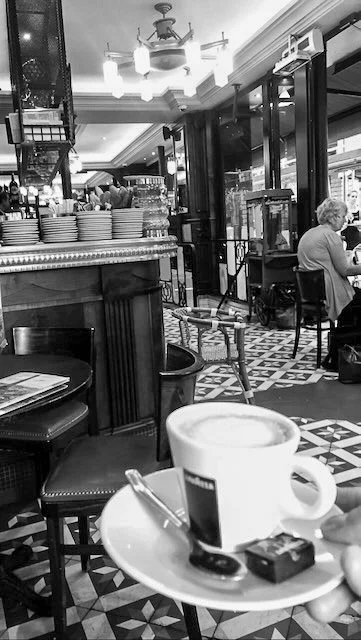 “Black and white European café interior with tiled flooring and soft morning light.”