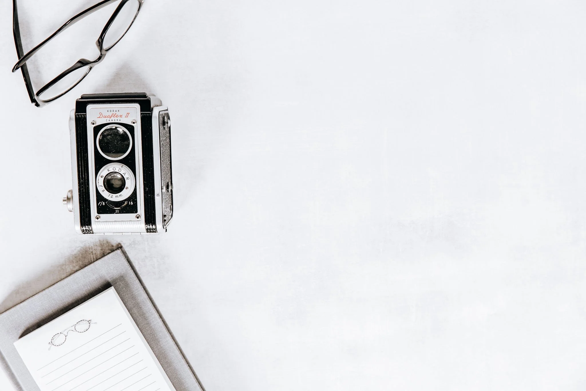 A clean, minimalist workspace with a vintage camera, journals and neutral stationery — representing refinement, rebranding and intentional evolution.