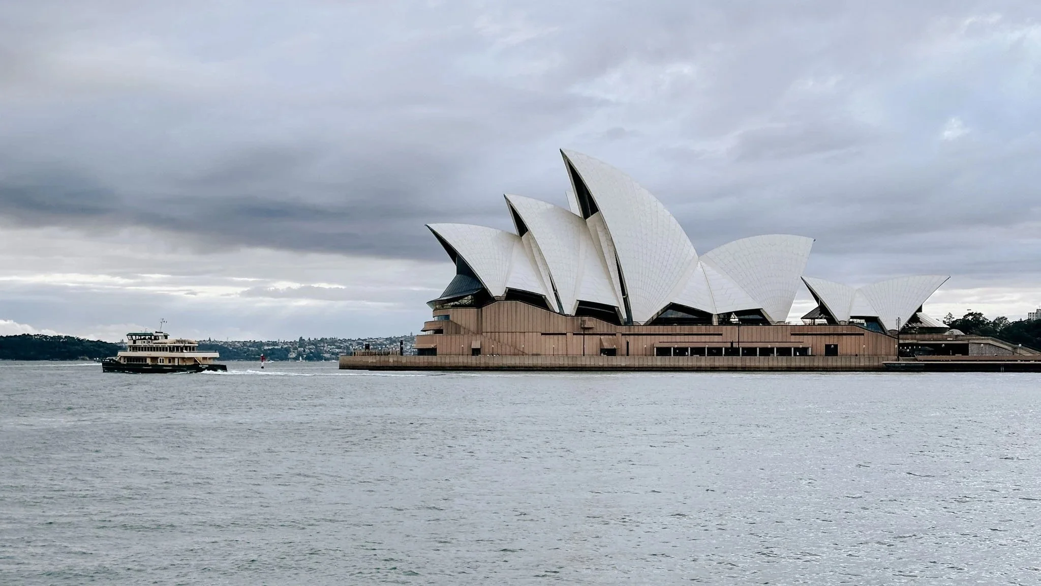 “Sydney Opera House overlooking the harbour at sunset, viewed from above with the city in the background.”
