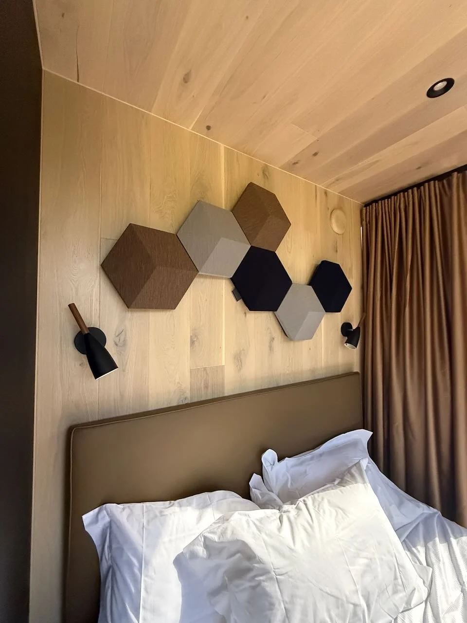 bedroom with wooden walls geometric panels and white bedding inside the ood house