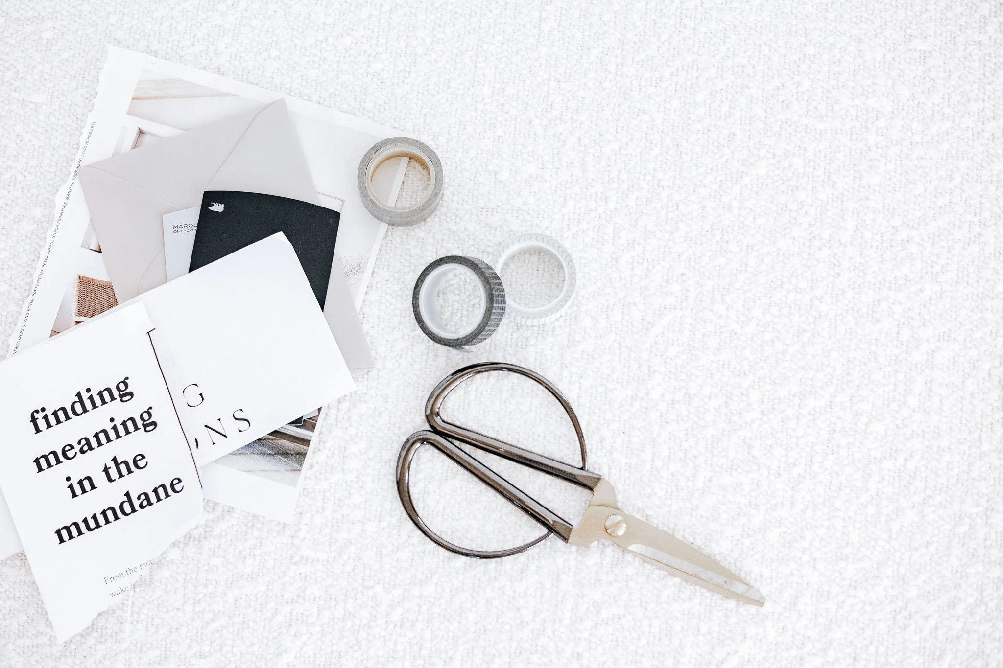 Minimal flat lay of typography cut-outs, envelopes and brass scissors on a textured neutral surface — a soft visual study of fonts, layout and editorial design tools.