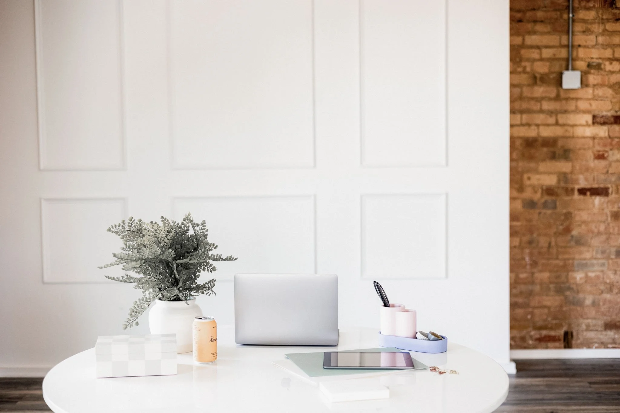 Wide view of a calm workspace with plant, laptop and white desk — a layout designed for flow, light and gentle productivity.