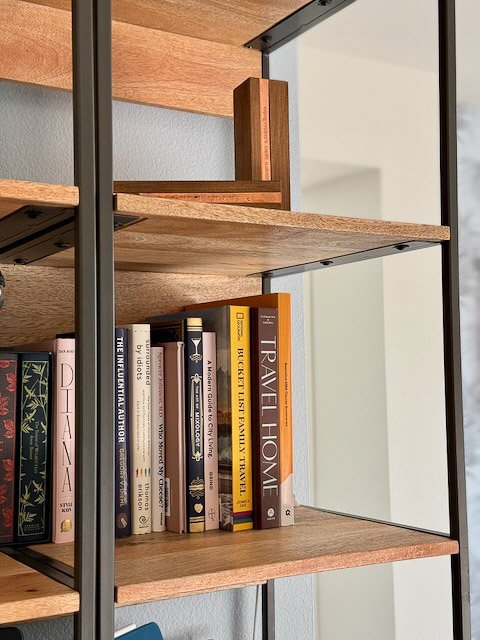 “Minimal open bookshelf with warm wood shelves and curated design books.”