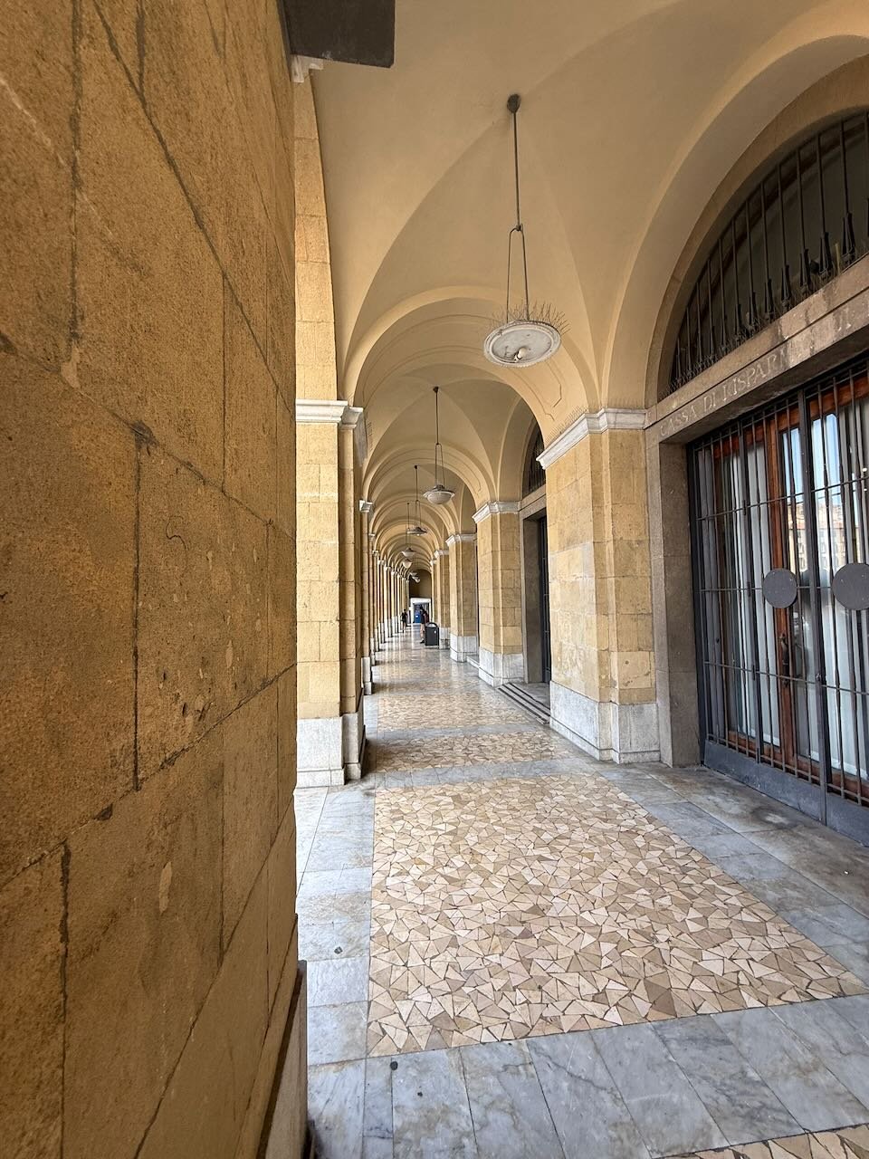 long stone arcade walkway with arches and soft light in an italian city