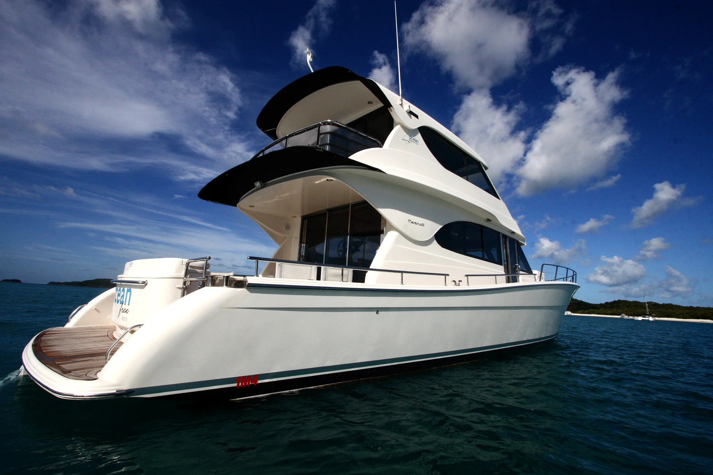 A large white yacht on the water under a partly cloudy blue sky.