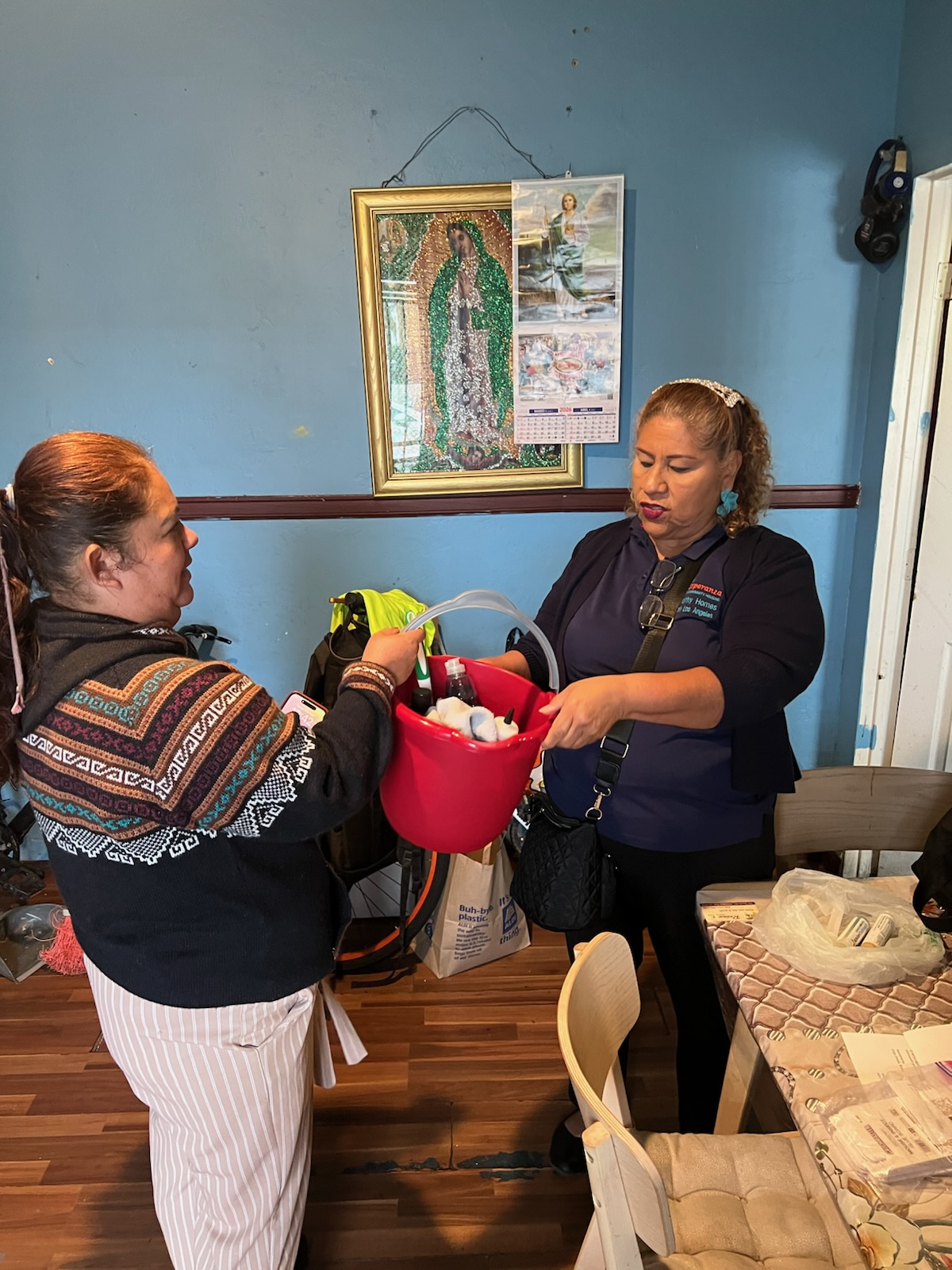 Our community health promoter, Maria, gives a bucket of cleaning supplies to a community member during a home visit.