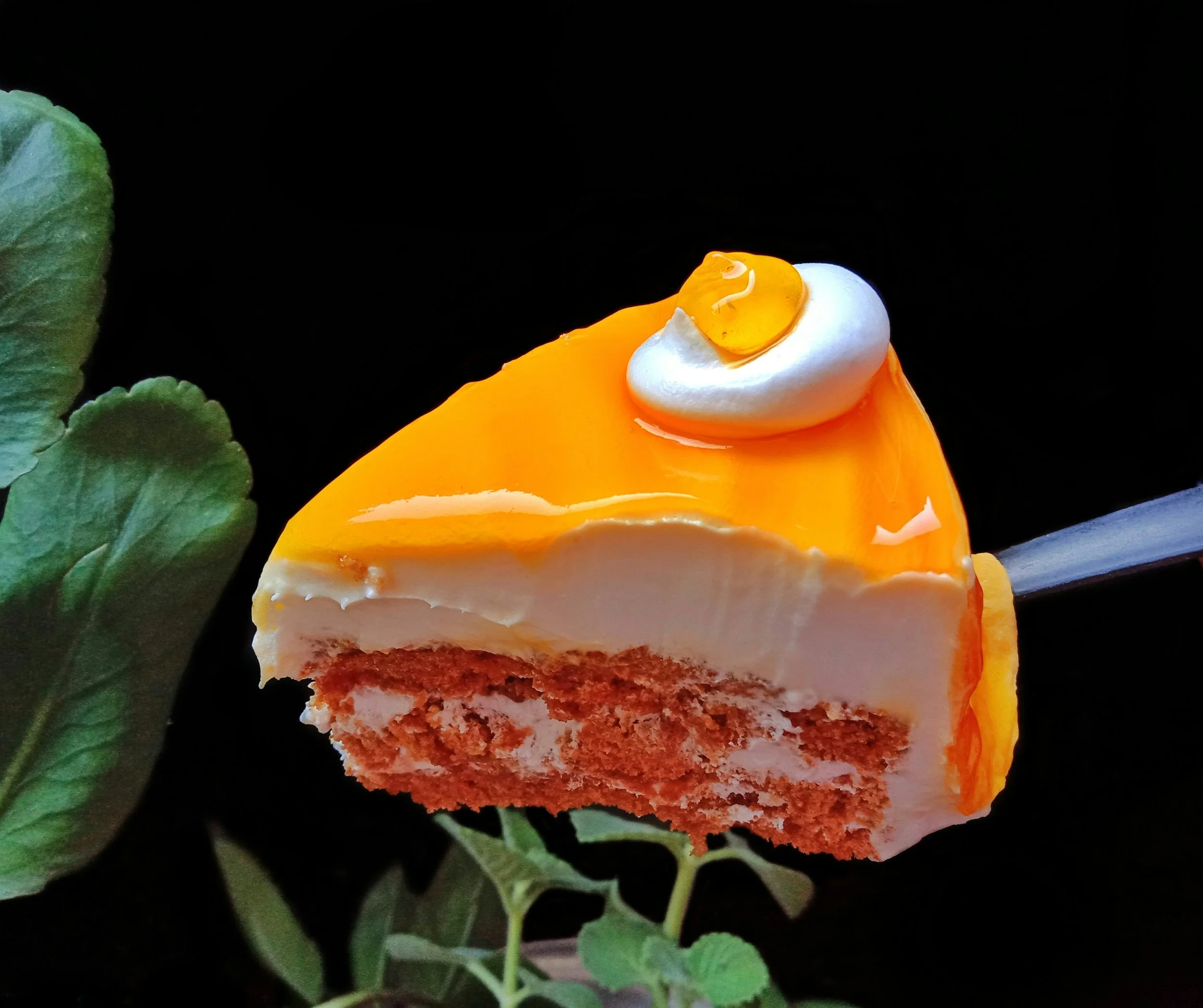A decadent orange-colored dessert with greens in the background