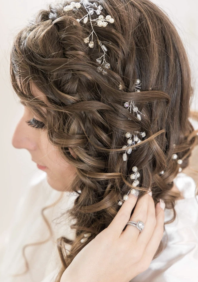 Close-up of a woman's curly hair adorned with a decorative hair accessory featuring pearls and crystals.