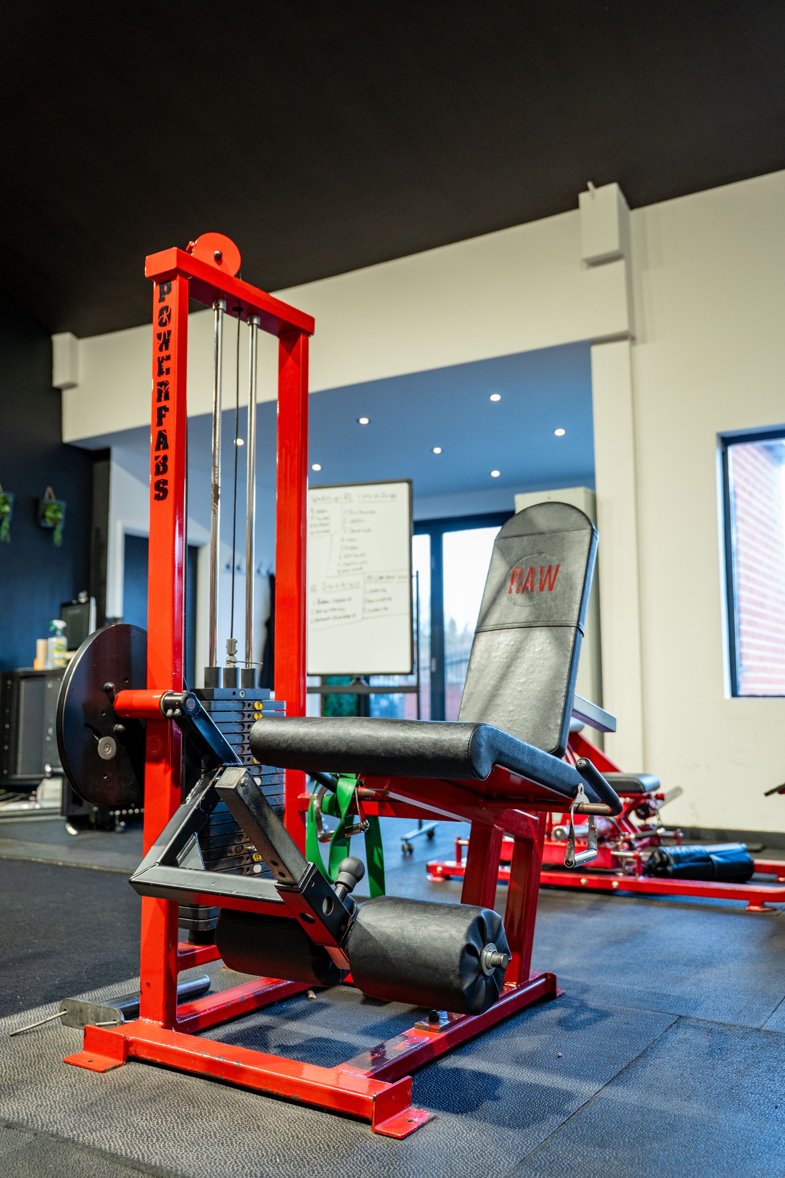 Red and black exercise equipment in a gym with windows and a whiteboard in the background.