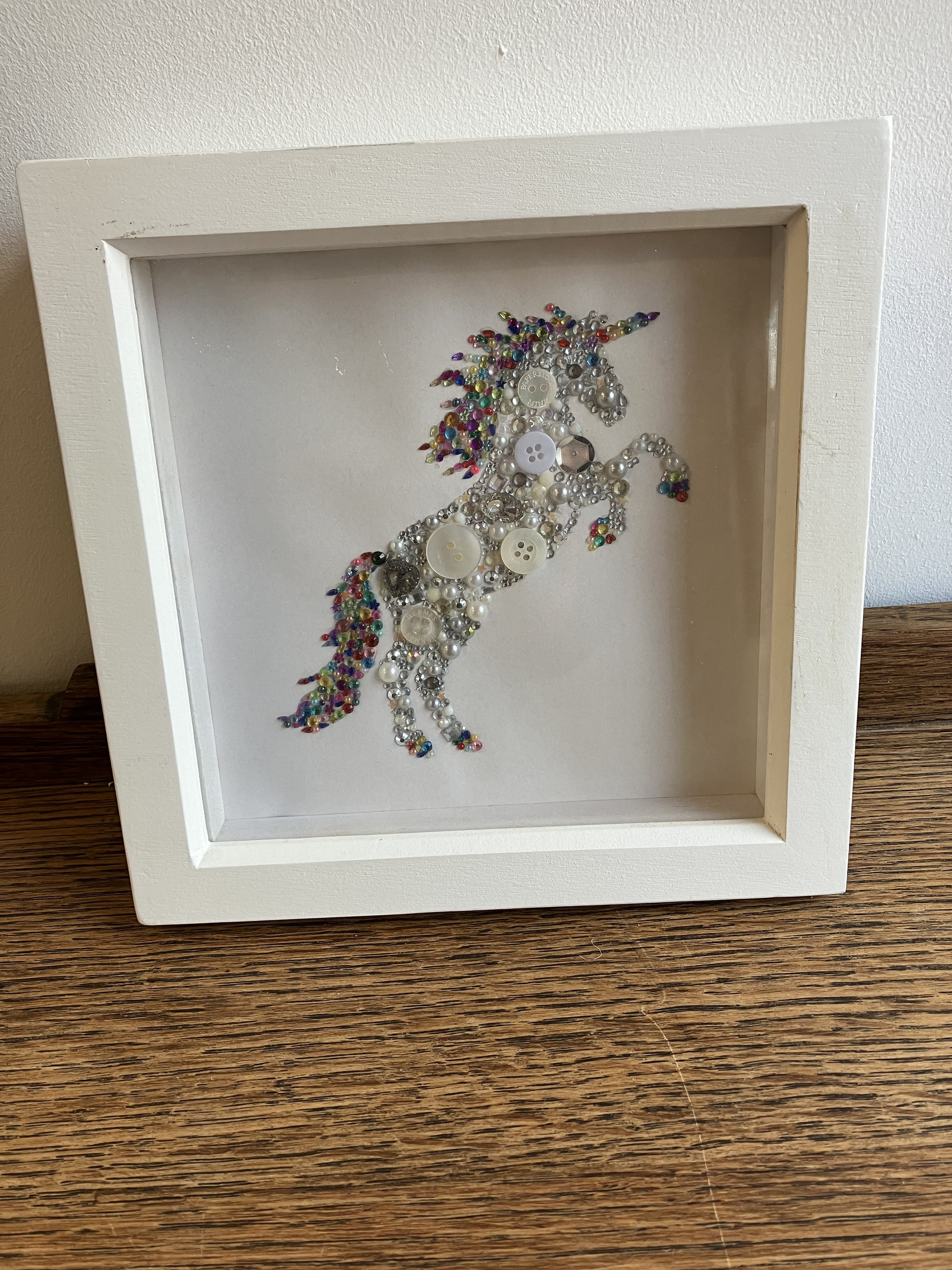 Unicorn Button Artwork Mounted in a White Box Frame