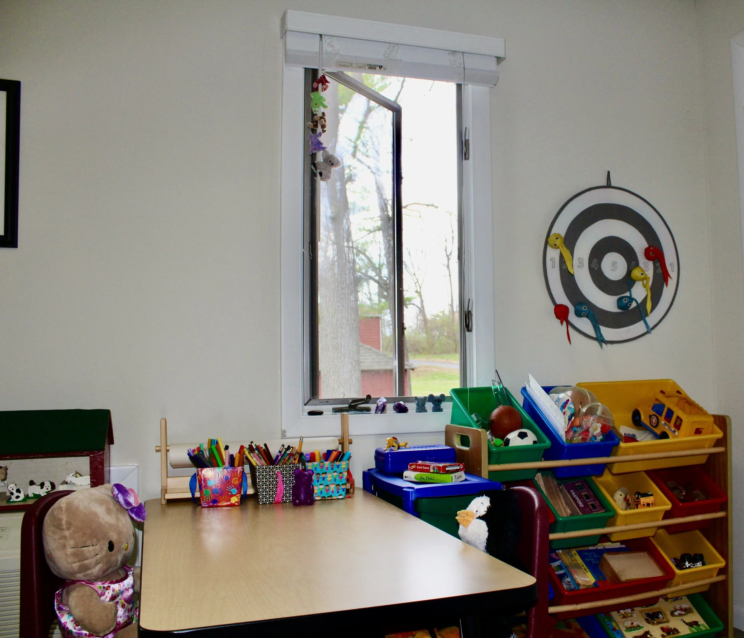 Office has window views of trees, and child friendly table, toys, games, art supplies and books.