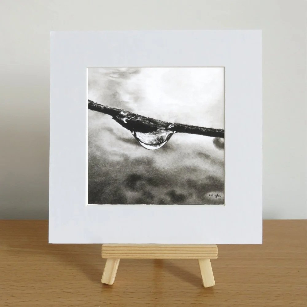 A photo of an artwork on an easel. It shows a branch or a rope with a water droplet