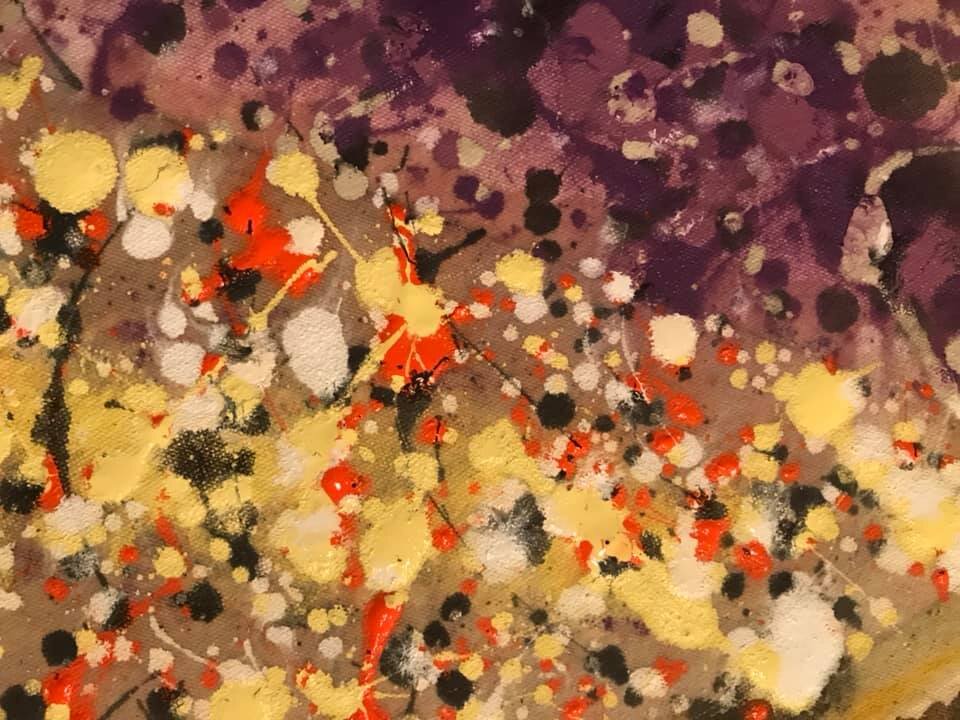 A close-up of the splatter-and-drip technique showing 10 different colors of paint that create the effect of two main colors in the overall design (yellow and purple).