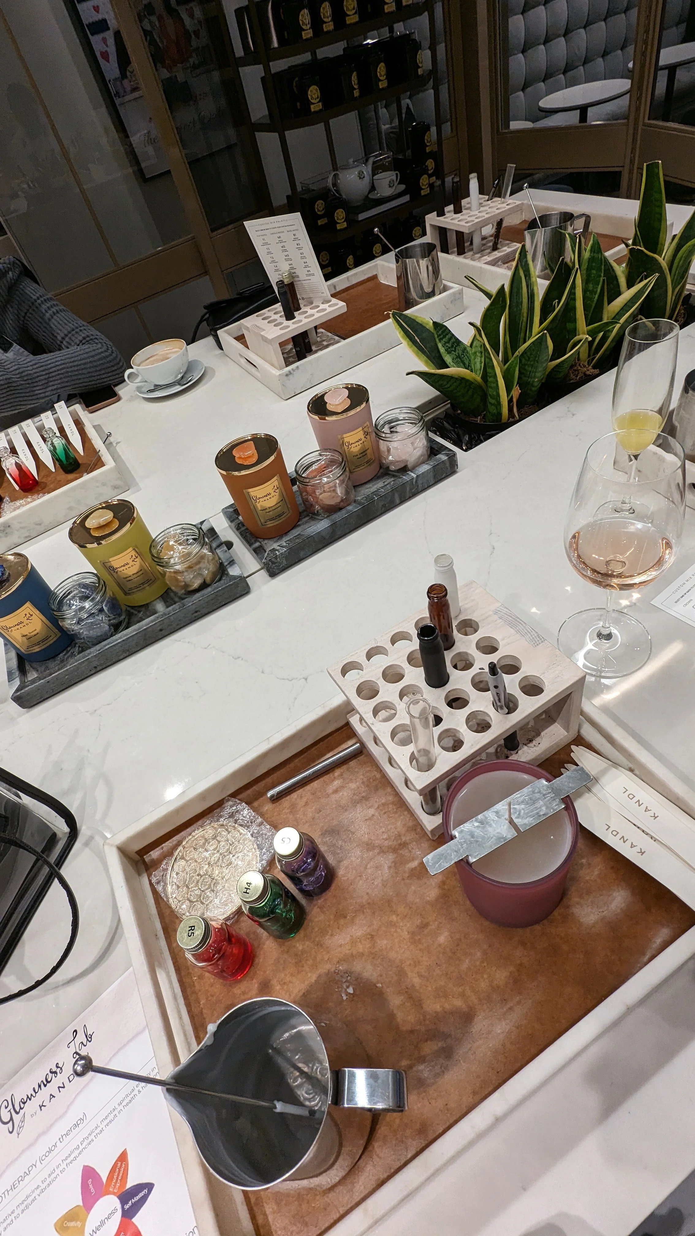 A countertop with candles, test tubes, and a test tube holder, along with pens, glassware, and a potted plant.