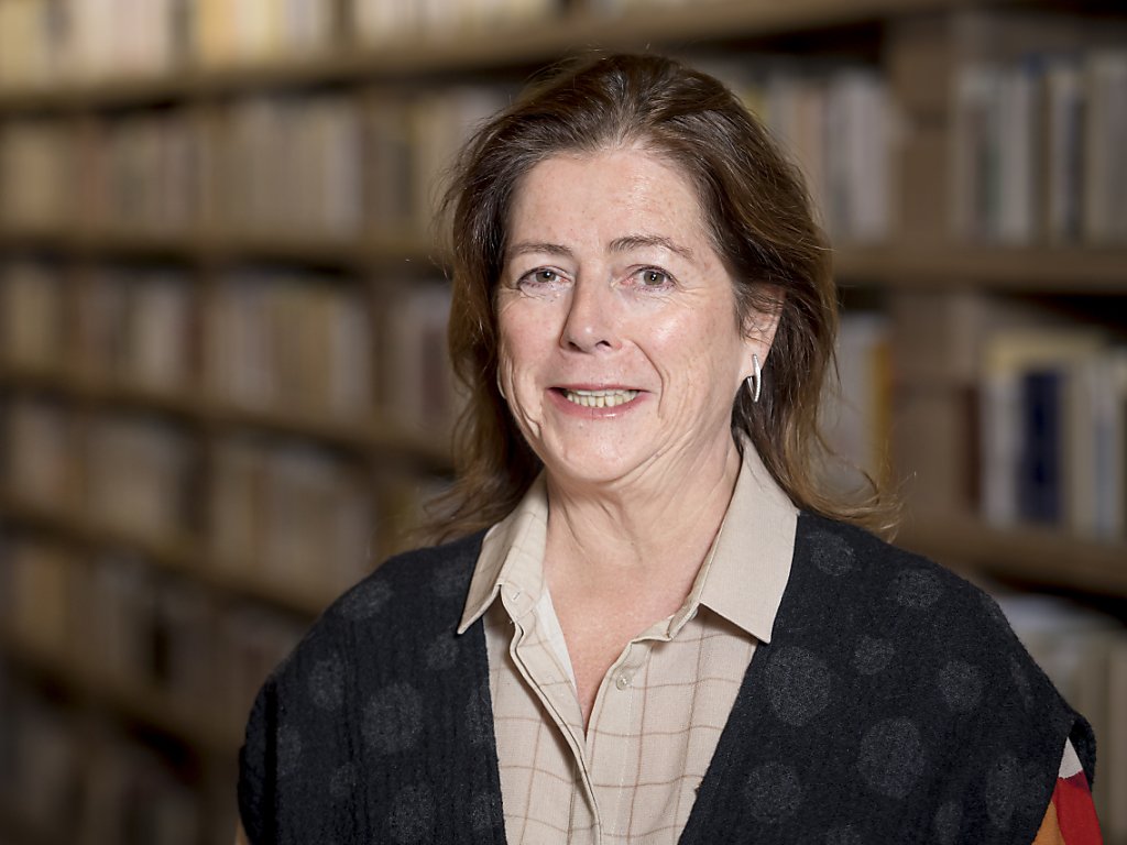 A woman smiling in a library, with bookshelves in the background.