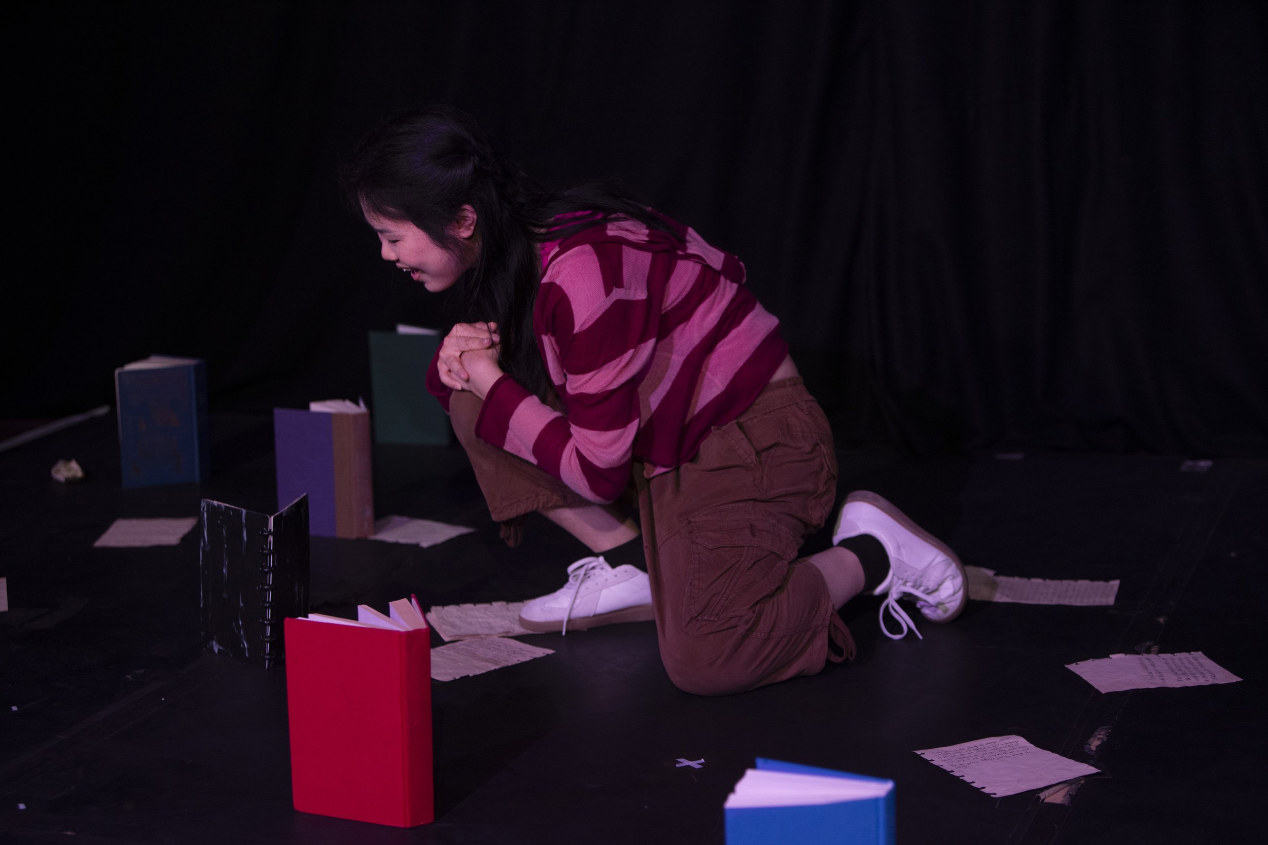Actor Lan Jiang on stage in the show, surrounded by books and paper