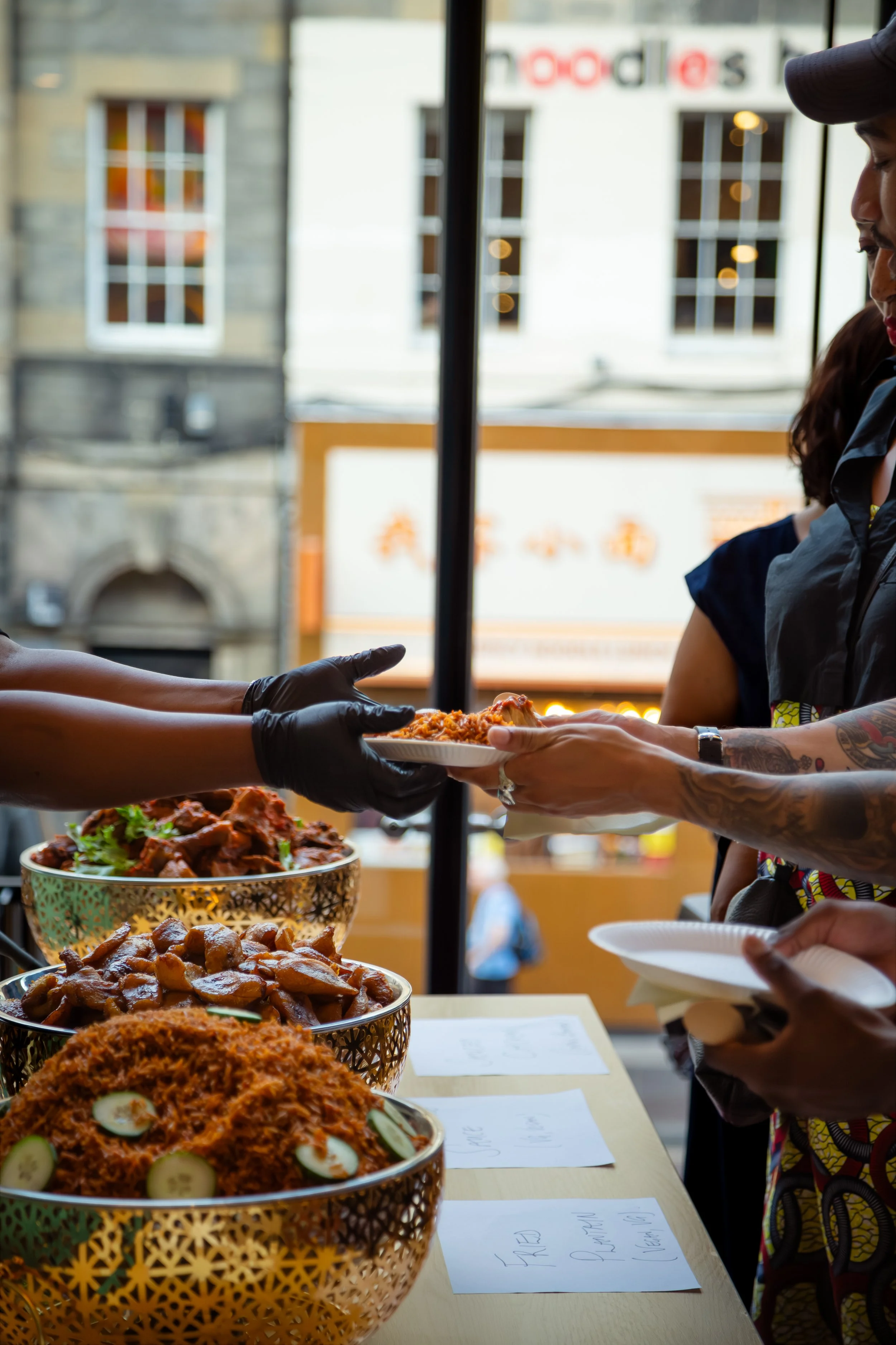 Photo of a chef handing a Fringe of Colour party attendees a plate of jollof