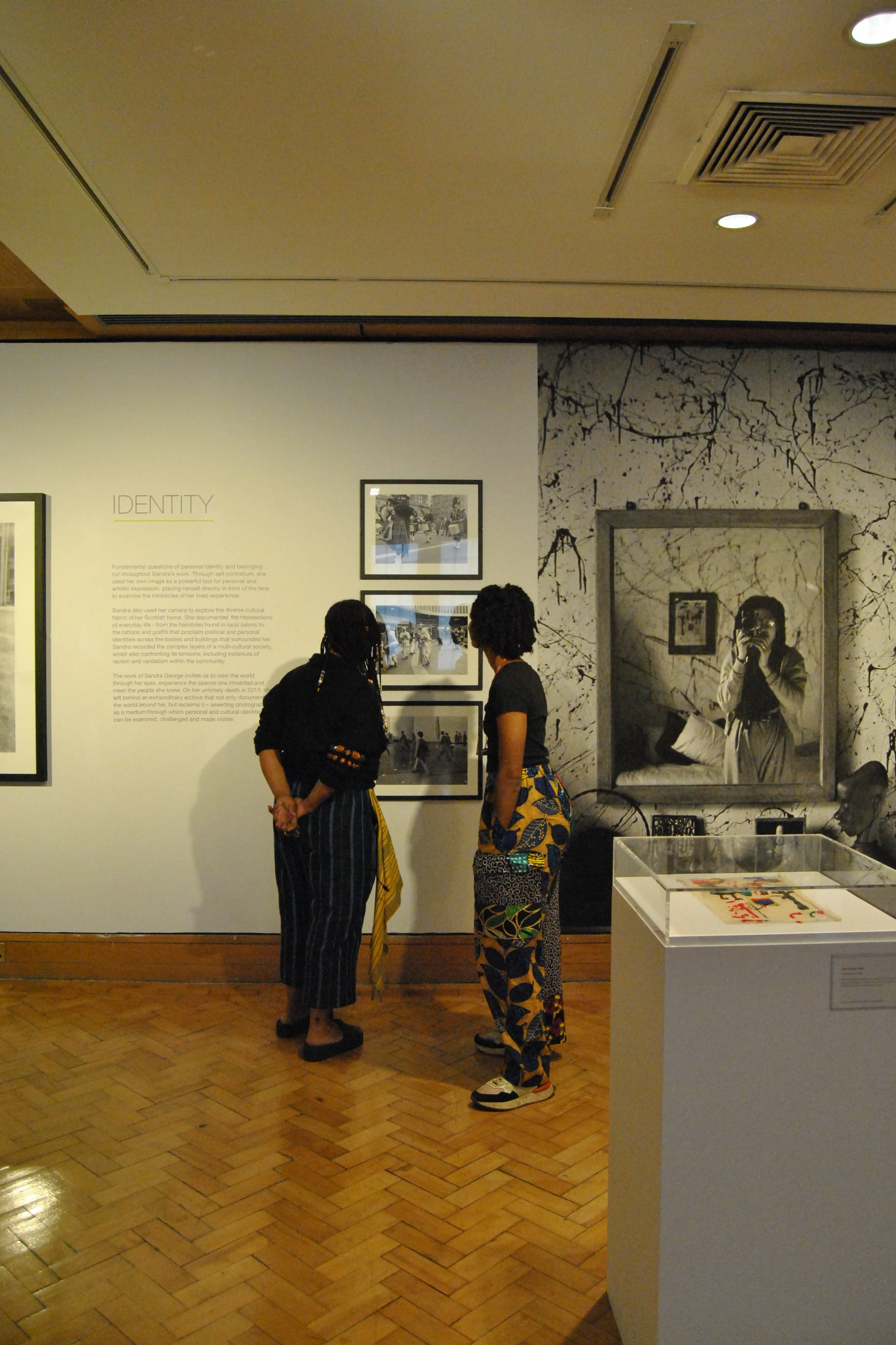 Two friends from the group looking at photos in the IDENTITY section of Sandra's exhibition