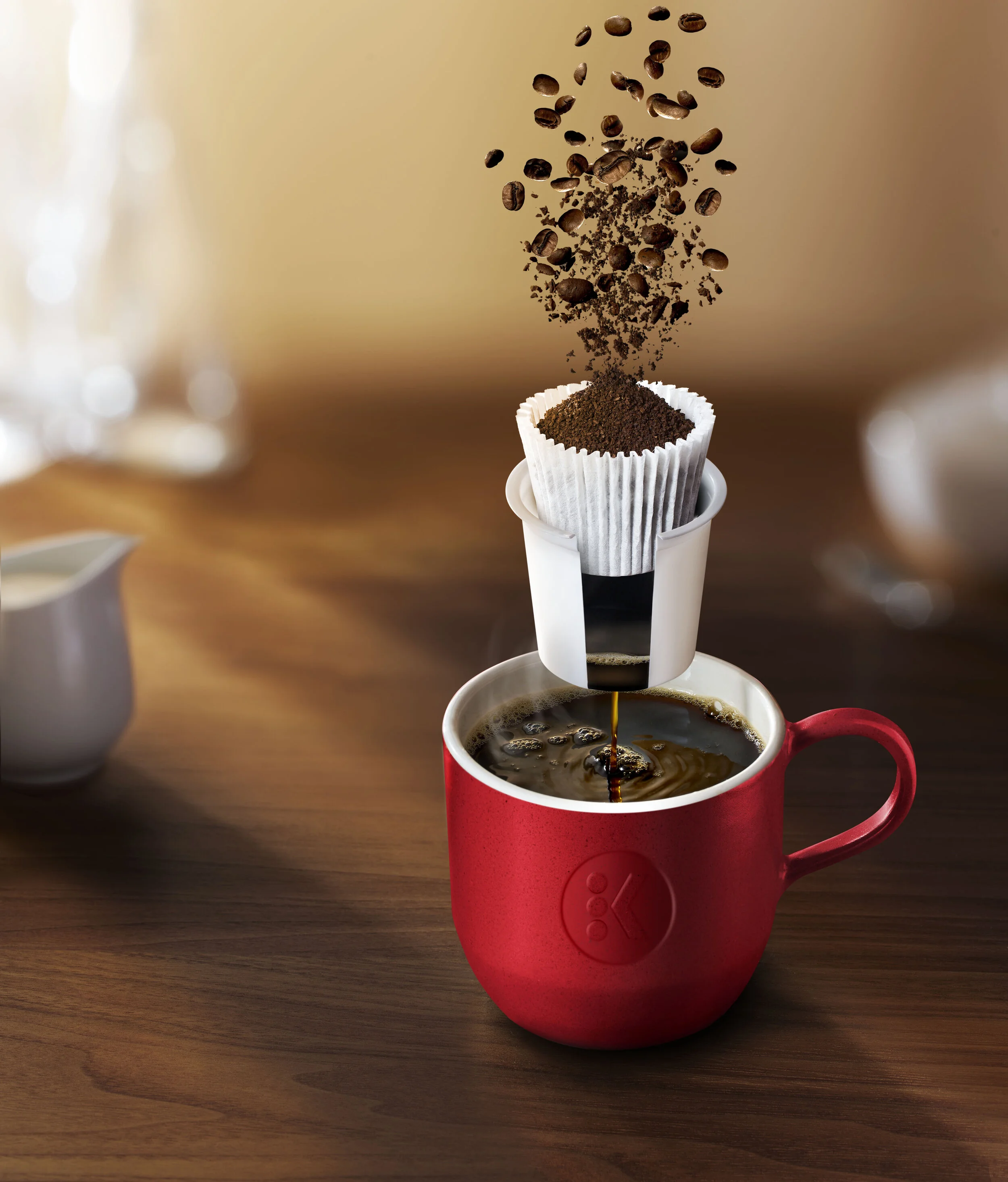 Coffee brewing setup with coffee beans, filter, red mug, and drip process on a wooden surface.