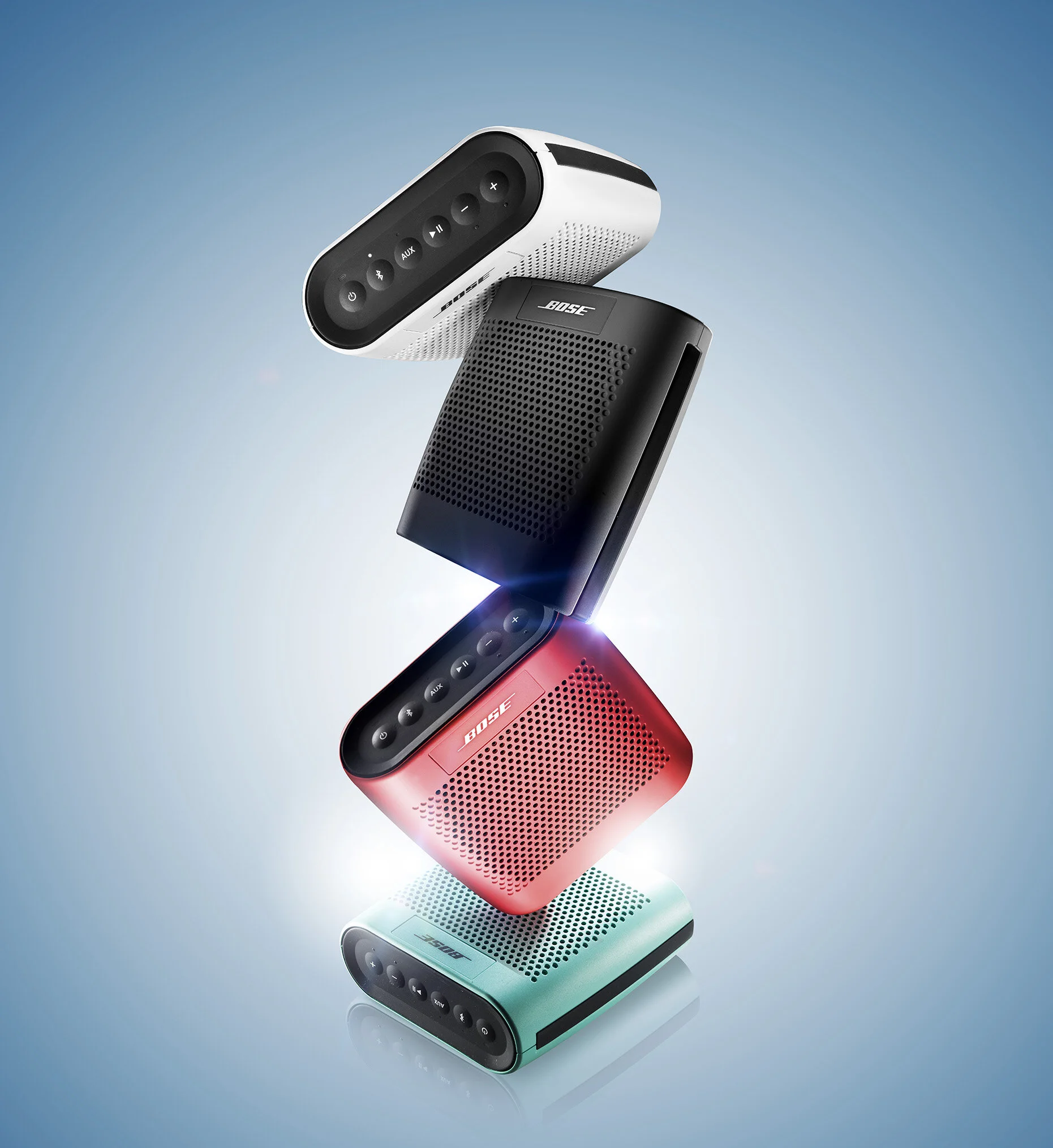 Stack of four colorful portable speakers against a gradient background