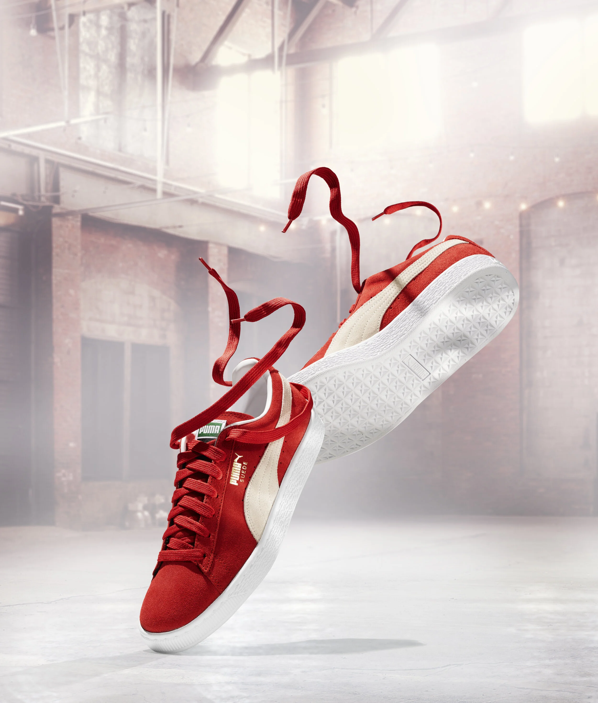 Red Puma sneakers with white soles in a warehouse setting.