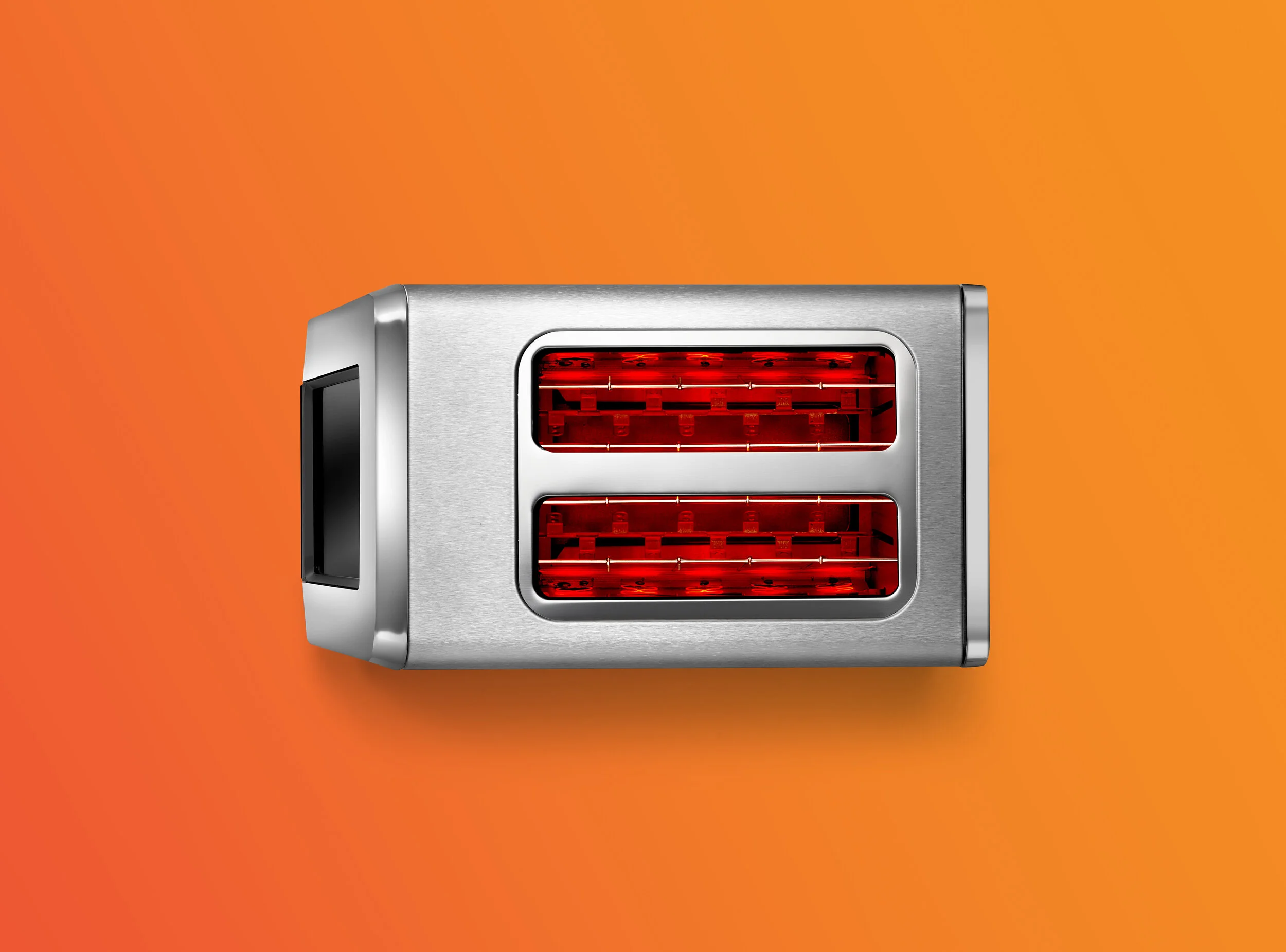 Stainless steel toaster with two slots, glowing red, on orange background