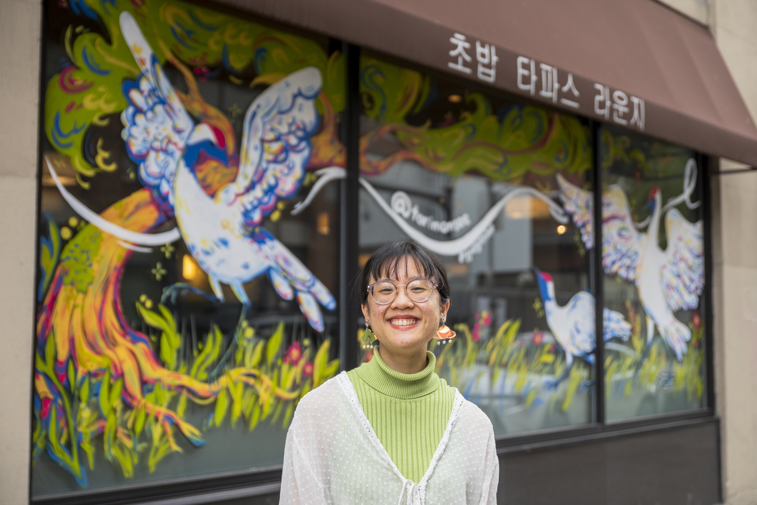 Victoria Lai in front of her and Jenny Tran's mural, "Wing to Wing," at Crave Chinatown