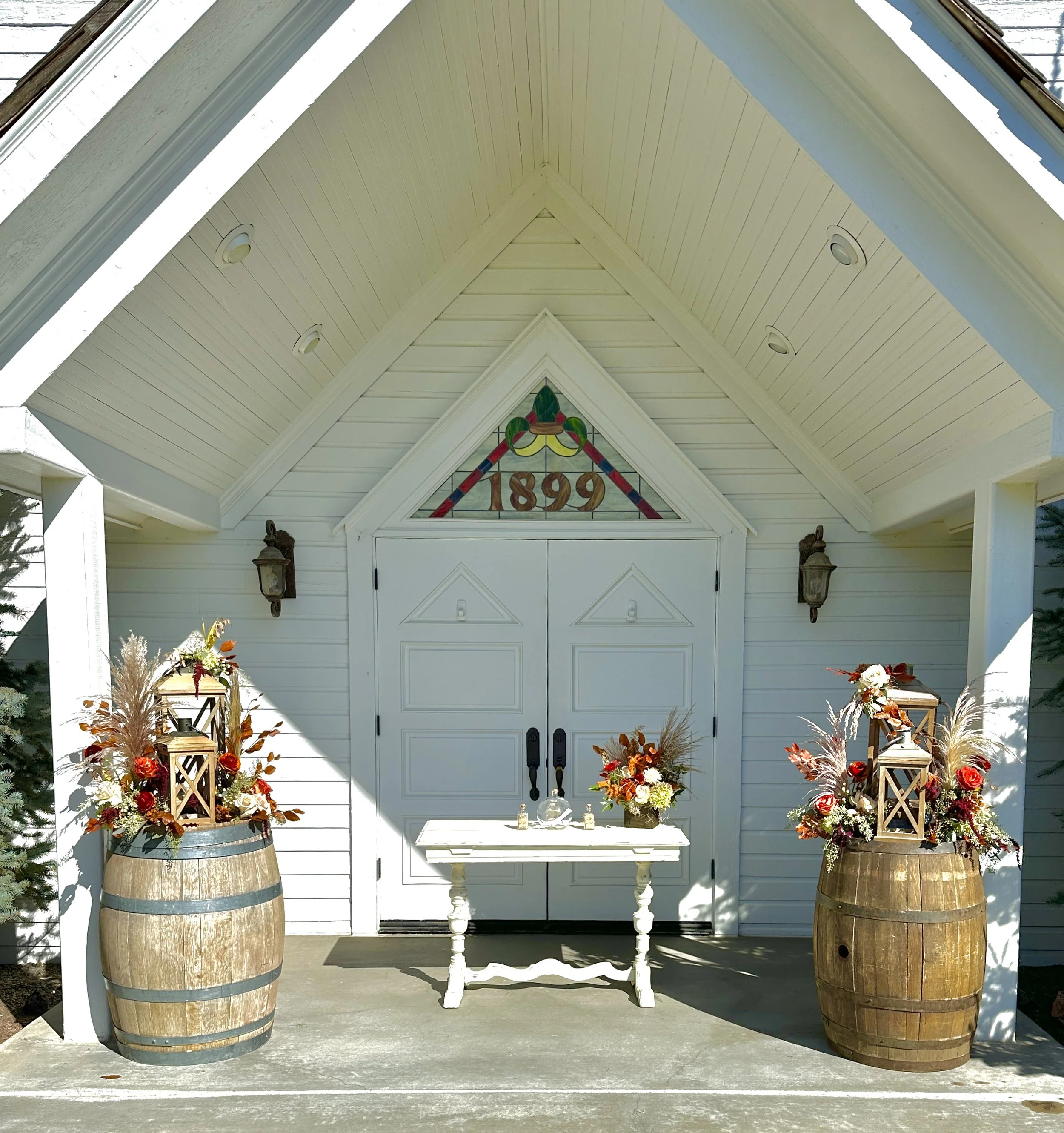 Outdoor wedding reception flowers sit on two large wooden barrels for an autumn wedding. Wedding flowers by Boise florist Edwards Flowershop.
