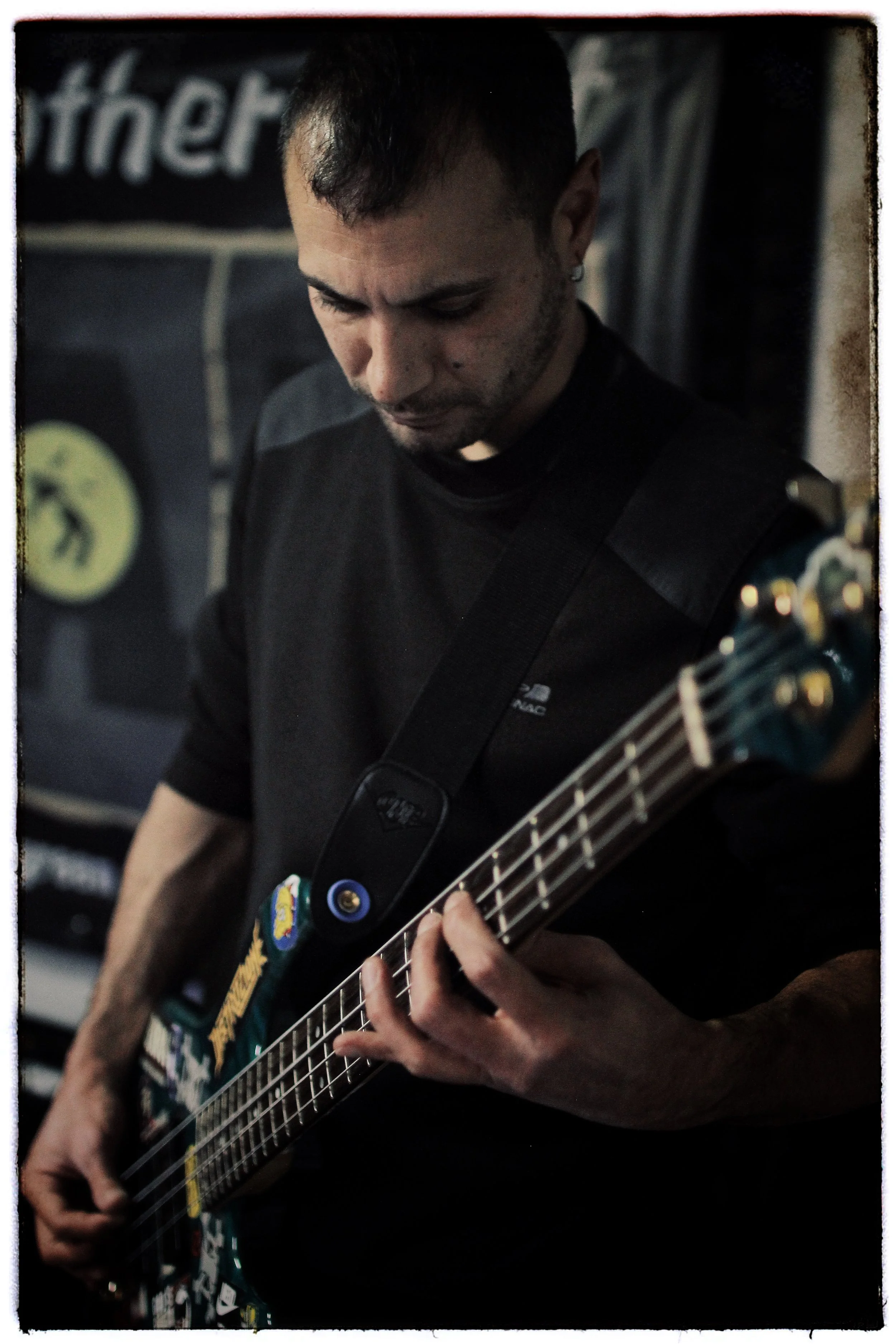 A man playing an electric guitar in a dimly lit setting, focused on strumming.